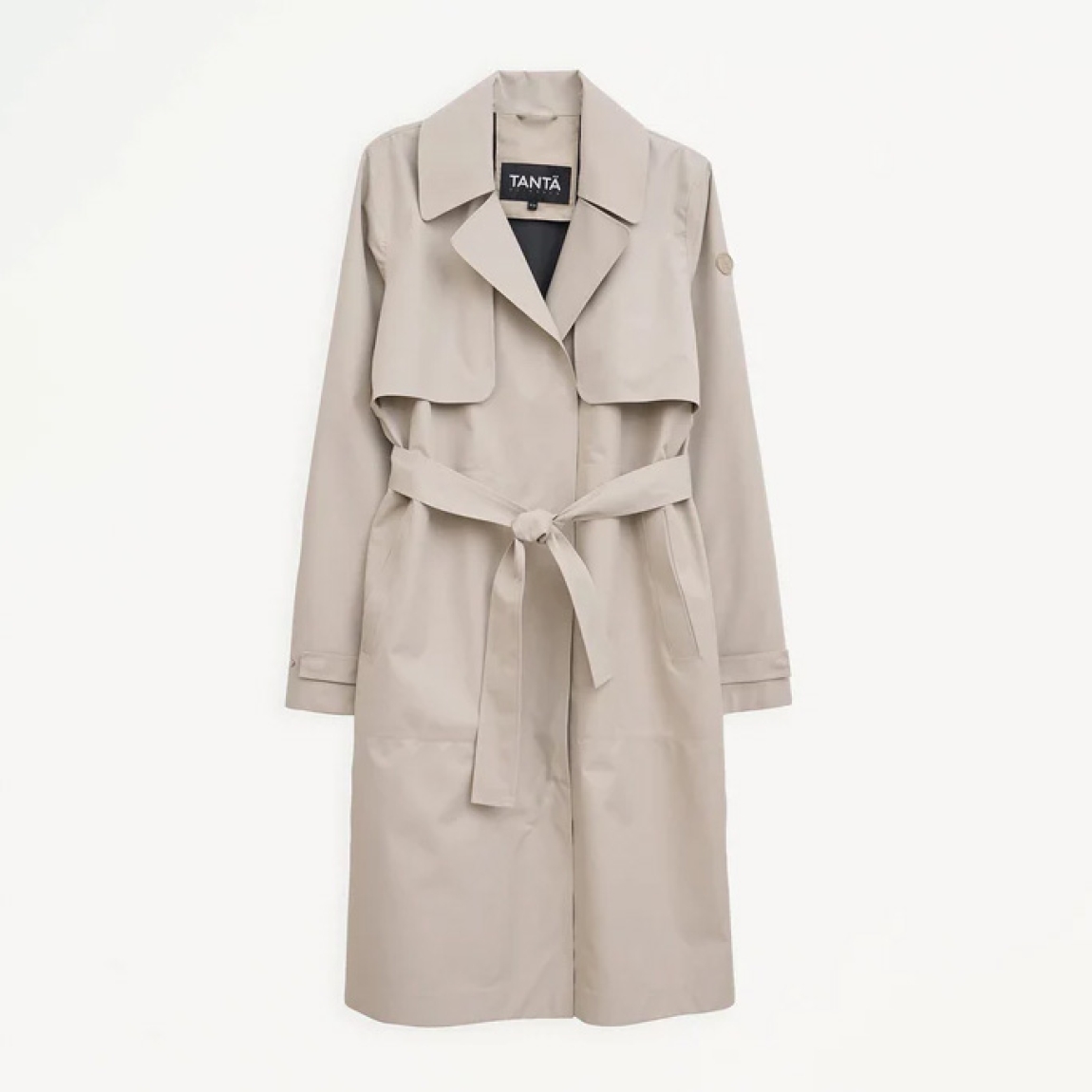 Chaqueta lisa larga de la marca Tanta, modelo TAGE. Chaqueta o gabarina impermeable sin costuras Tage está confeccionado en tejido de sarga de poliéster color beig. Es 100% impermeable y cuenta con todas las costuras selladas para una protección superior. Los detalles de la prenda incluyen dos canesús en la parte delantera y uno en la parte trasera, botones a presión ocultos, una cintura ajustable con cinturón y una capucha desmontable con cordón ajustable. Chaqueta Tanta dieñada con un corte impecable, el modelo Tage de Tanta combina elegancia con una alta funcionalidad.