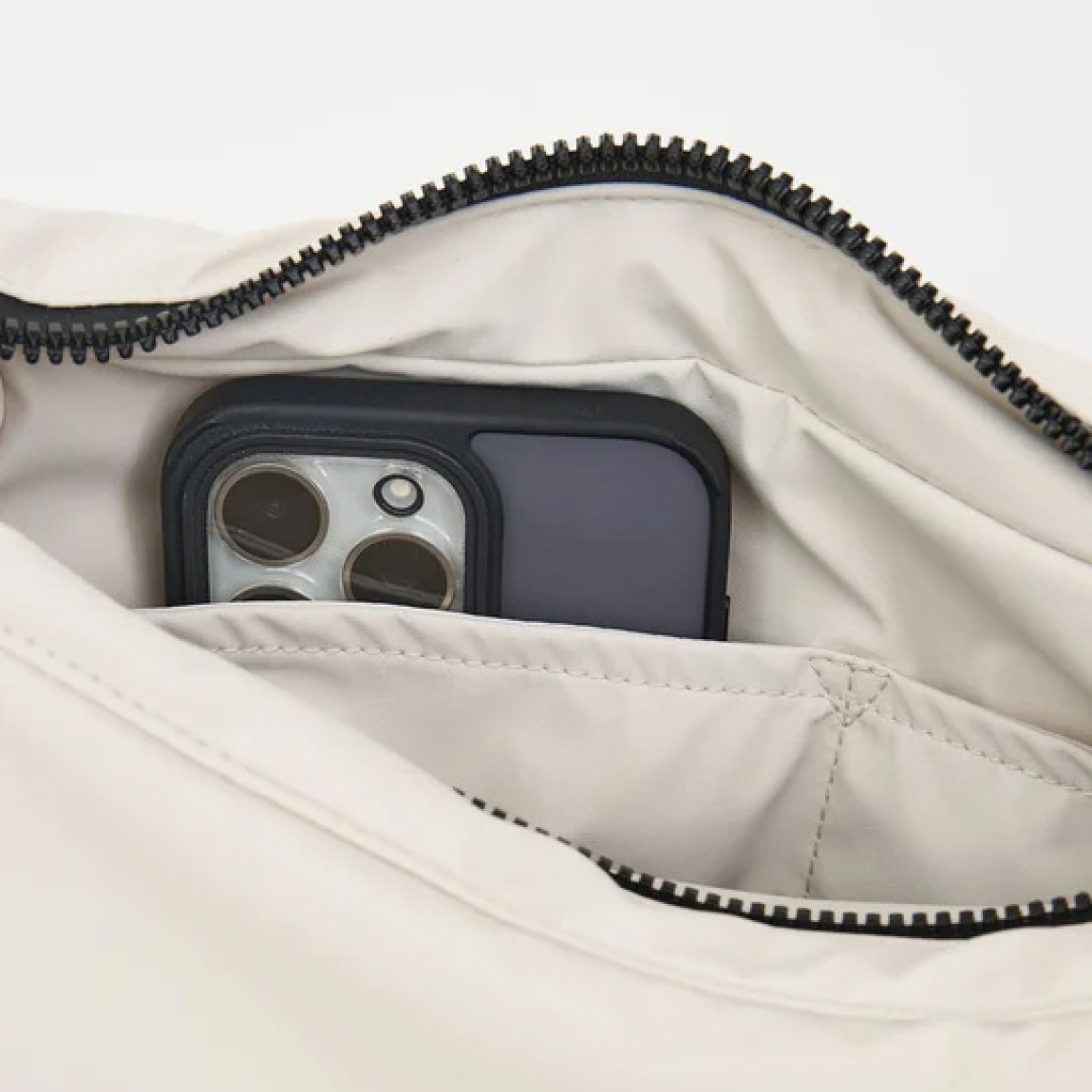 Bolso de la marca Tanta, modelo KUHIRÓ. Este bolso Tanta Kuhiró es un bolso de tamaño medio fabricado en Softshell ligero color blanco con un acabado repelente al agua duradero. Los detalles del bolso Tanta incluyen un diseño curvado, una correa ajustable y un compartimento principal con una gruesa cremallera. Este modelo Kuhiró de Tanta, es un bolso versátil que puede llevarse al hombro o cruzado. Medidas: alto 22cm y ancho 32cm.