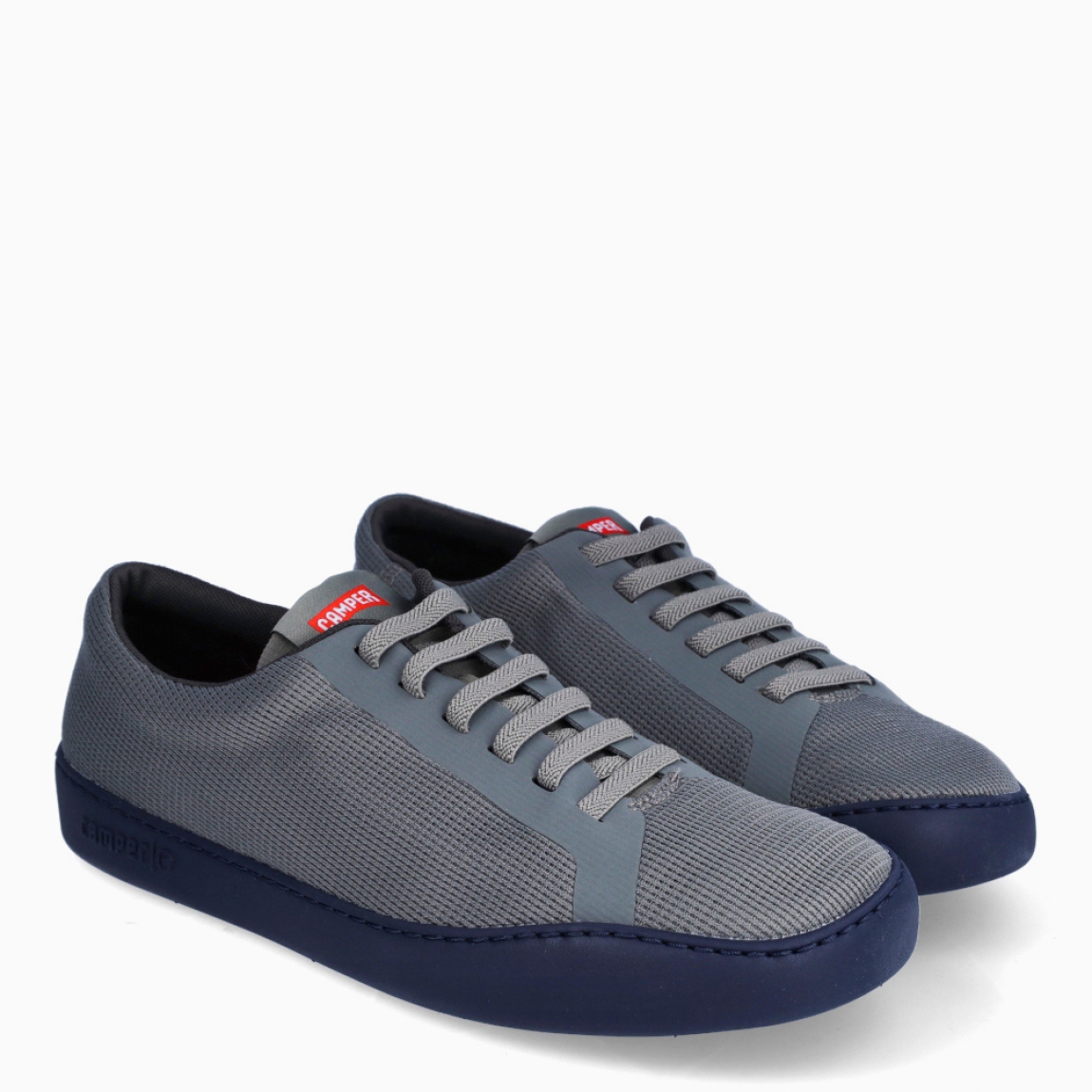 Deportivas de la marca Camper, modelo K82. Exterior en textil color gris con efecto rejilla y detalle del logo. Deportivas clásicas con cierre de cordones en pala color gris. Suela de goma plana. Estas deportivas Camper K82 son unas clásicas, ideales para tu día a día!