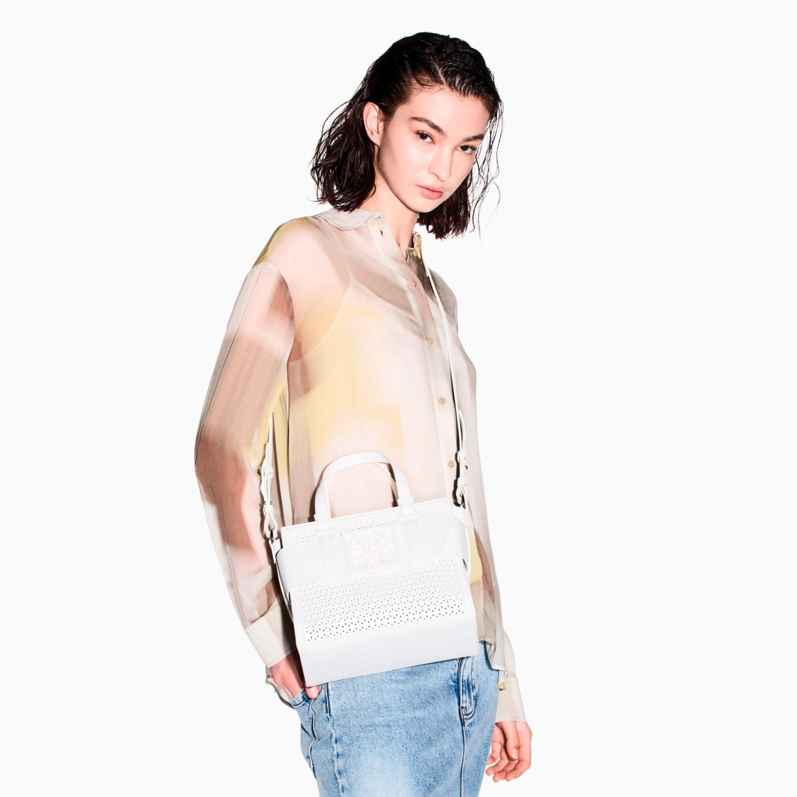 Bolso de la marca Armani Exchange, modelo URSULA. Bolso con diseño minimalista elaborado en piel con efecto troquelado color blanco, y detalle de logotipo en parte frontal. Cierre con cremallera. Bolso perfecto para completar looks urbanos y sofisticados. La textura técnica del tejido le aporta un toque moderno y resistente, mientras que su gran capacidad lo hace ideal para afrontar el día con estilo y practicidad. Bolso Armani Exchange con amplio compartimento principal. Se puede llevar al hombro o en la mano. Bolso Amani Exchange URSULA, es un accesorio imprescindible para quienes aprecian la sencillez refinada. Medidas: alto 20cm y ancho 24cm.