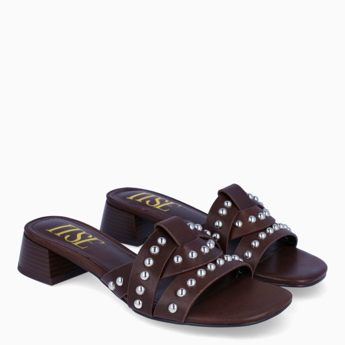 Sandalias de la marca Itse, modelo NOAH. Sandalias elaboradas en piel color marrón con tiras cruzadas en pala con detalles de tachuelas plateadas. Interior de sandalias en piel color marrón. Sandalias destalonadas con tacón de 4cm de altura. Sandas Itse NOAH, complemento ideal de temporda!