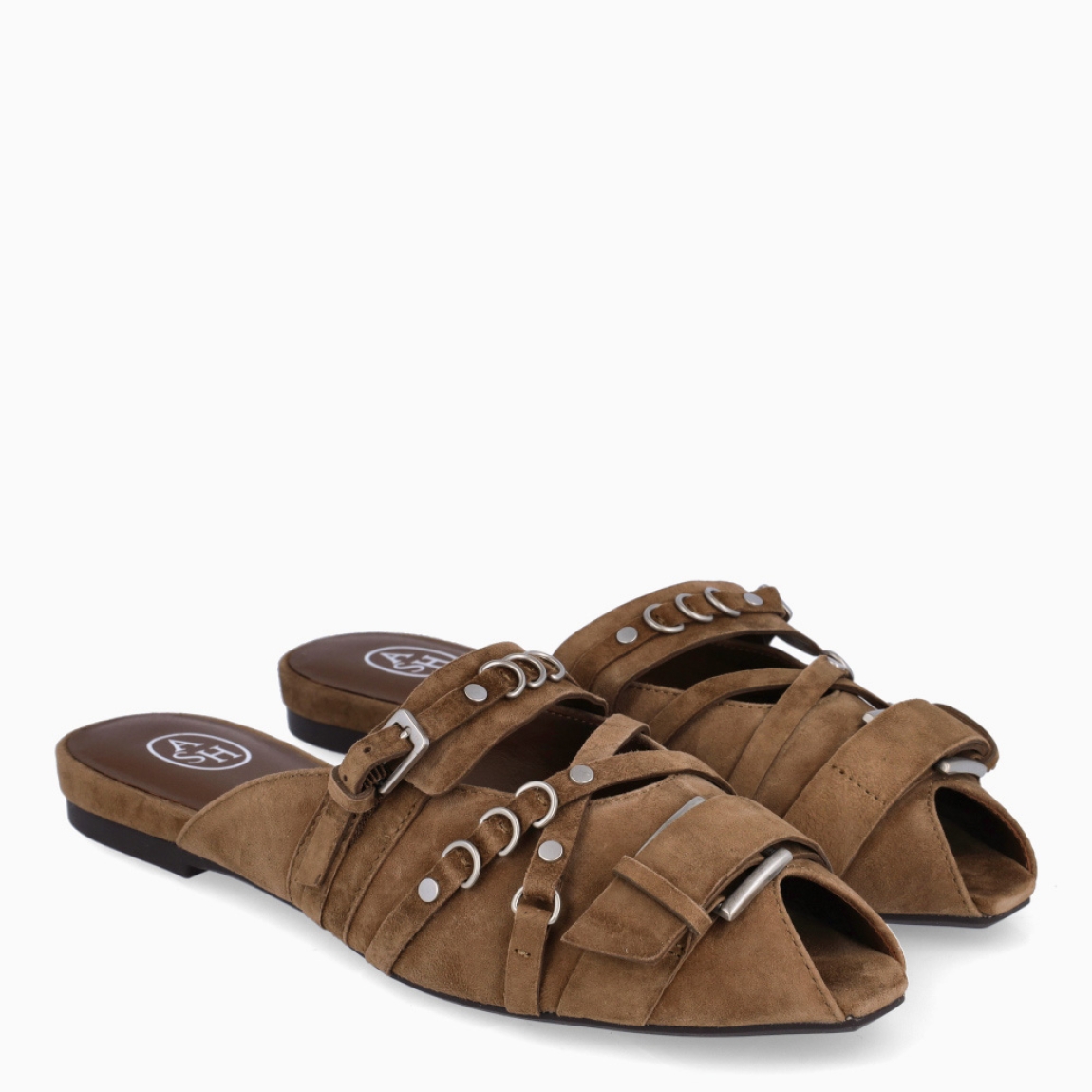 Zuecos de la marca ASH, modelo BRIGIT. Elaborados en ante color marrón con detalle de hebillas en pala y tiras cruzadas. Punta abierta. Interior en ante color marrón. Suela plana. Zuecos ASH BRIGIT, complemento ideal para temporada!