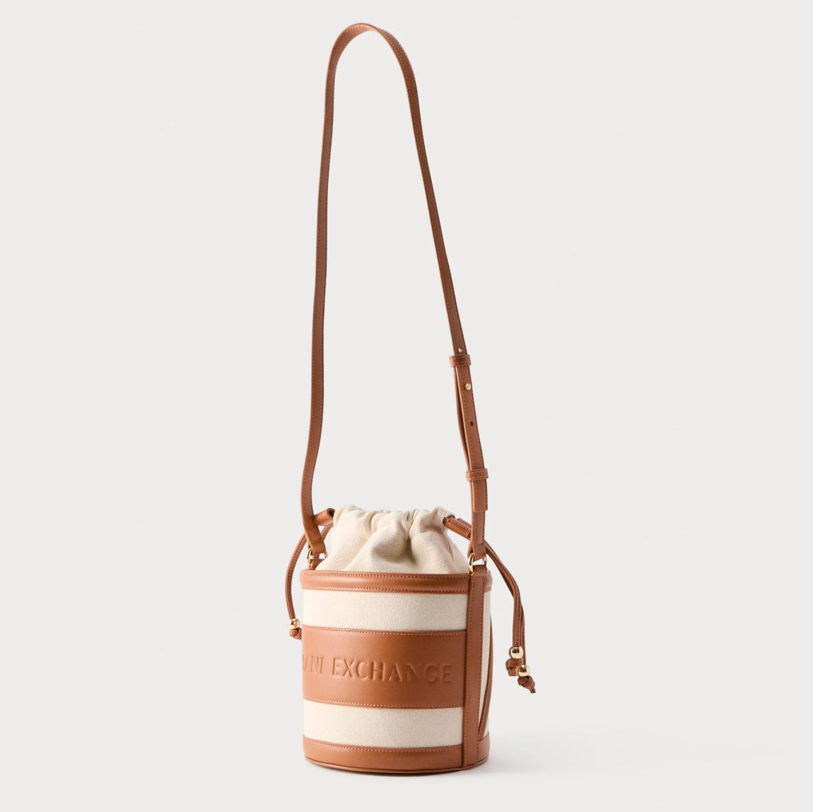Bolso tipo cubo de la marca Armani Exchange, modelo RACHEL. Bolso elaborado en polipiel color cuero. Tiene una silueta depurada, definida por líneas suaves y una paleta de colores neutros, se presta a innumerables combinaciones de estilo, con logo en todo el bolso. Con asas extraíbles de hombro. Bolso Armani Exchange RACHEL, un accesorio imprescindible para la mujer moderna que busca un toque de lujo discreto, perfecto para guardar sus secretos cotidianos con elegancia y sofisticación.