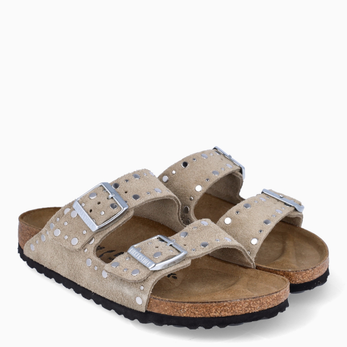 Sandalias de la marca Birkenstock, modelo ARIZONA RIVET. Sandalias elaboradas en ante de color taupe con detalle de tachuelas y con una base de corcho y látex de forma anatómica. Cierre de las sandalias con doble hebilla de espiga de metal con ajuste individual. Estas sandalias Birkenstock ARIZONA RIVET es un complemento clásico para tus looks de temporada, con un diseño sencillo atemporal y una ligereza que te dará la comodidad que necesitas en tu día a día.