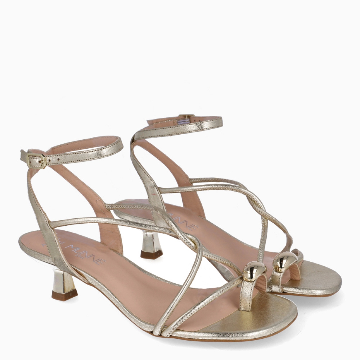 Sandalias de la marca Munné, modelo BRENDA. Elaboradas en piel color platino con tiras cruzadas en pala con detalle de anillo al dedo. Interior en piel color nude. Cierre de sandalias Munné con hebilla en tobillo y suela con tacón de 4cm de altura. Estas sandalias Munné BRENDA son ideales para elevar tu look con estilo!
