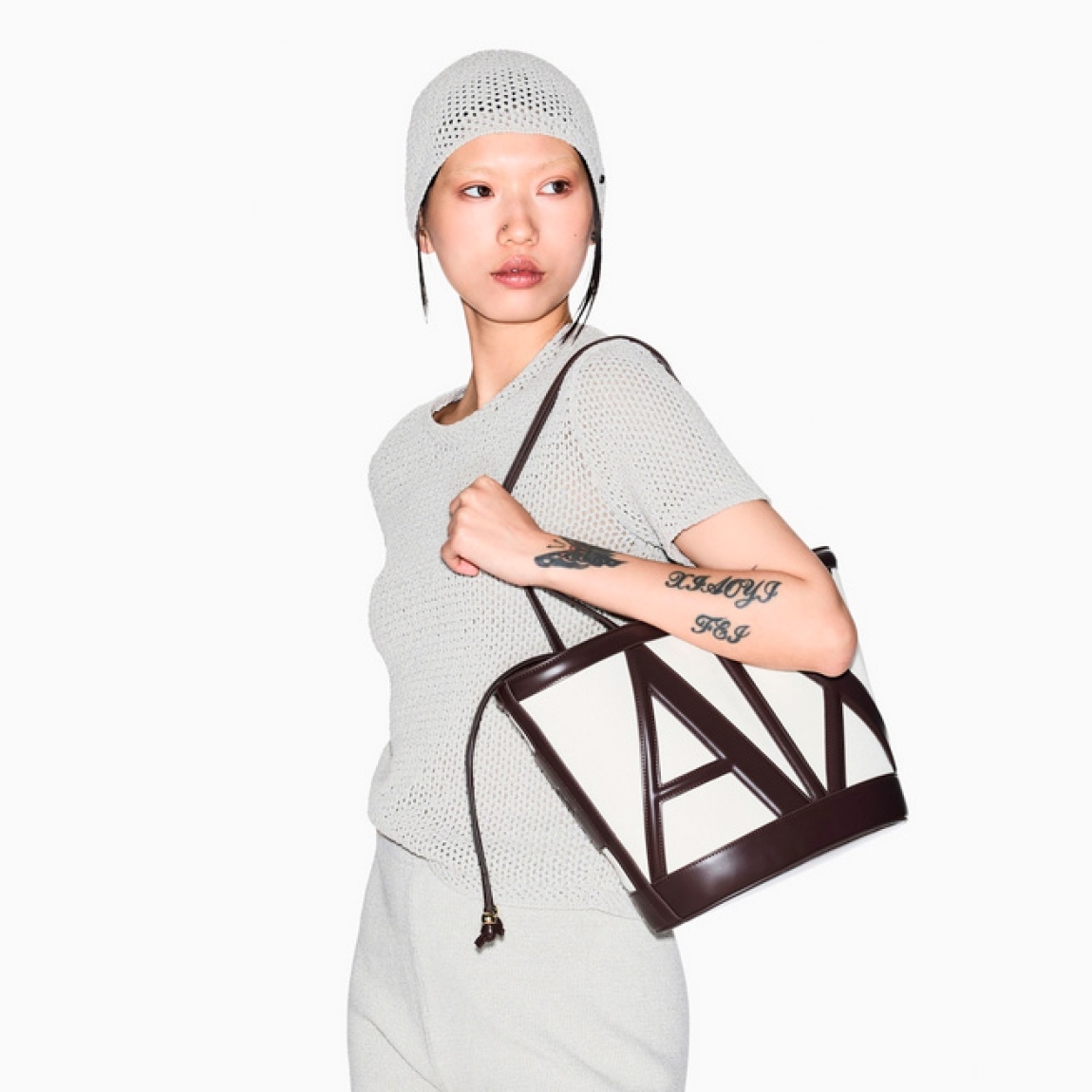 Bolso tipo cubo de la marca Armani Exchange, modelo RACHEL GRAN. Bolso elaborado en lona color marrón. Tiene una silueta depurada, definida por líneas suaves y una paleta de colores neutros, se presta a innumerables combinaciones de estilo, con logo en todo el bolso. Con asas extraíbles de hombro. Bolso Armani Exchange RACHEL GRAN, un accesorio imprescindible para la mujer moderna que busca un toque de lujo discreto, perfecto para guardar sus secretos cotidianos con elegancia y sofisticación.