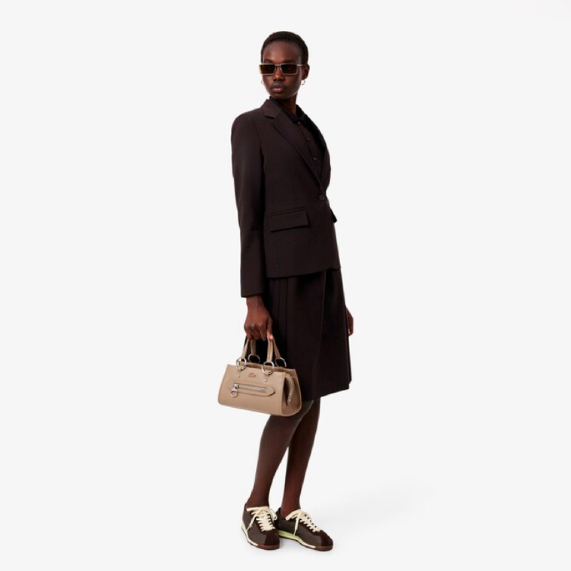 Bolso de la marca Lacoste, modelo CELYS. Elaborado en piel color taupe. Un bolso para llevar al hombro chic y desenfadado para hacer la transición del día a la noche con estilo. Su diseño intemporal incluye unos acabados sofisticados inspirados en el legado tenístico de Lacoste. Compacto, elegante y práctico, perfecto para usar a diario. Se adorna con un exclusivo cocodrilo metálico. Interior con bolsillo. Bolso para llevar al hombro o en bandolera, con Correa ajustable y amovible. Bolso Lacoste CELYS, ideal para llevarlo a todos lados! Medidas: alto 14cm y ancho 24cm.