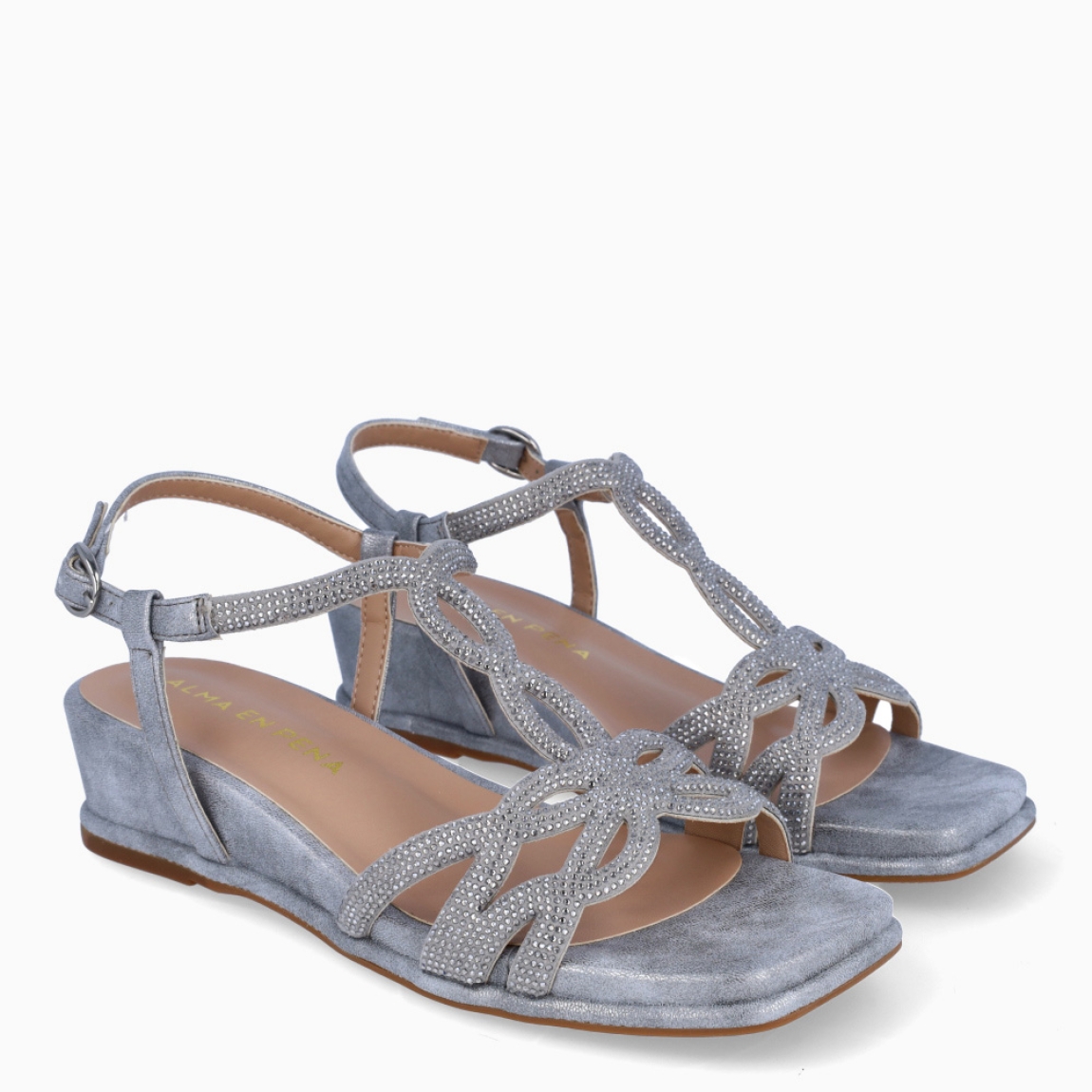 Sandalias de la marca Alma en Pena, modelo MINEA. Exterior de las sandalias en piel color plata con tiras en brillantes. Cierre de las sandalias con hebilla en el tobillo y cuña de 3cm de altura. Estas sandalias Alma en Pena MINEA son un complemento que le aportará estilo y comodidad a tus looks de temporada.