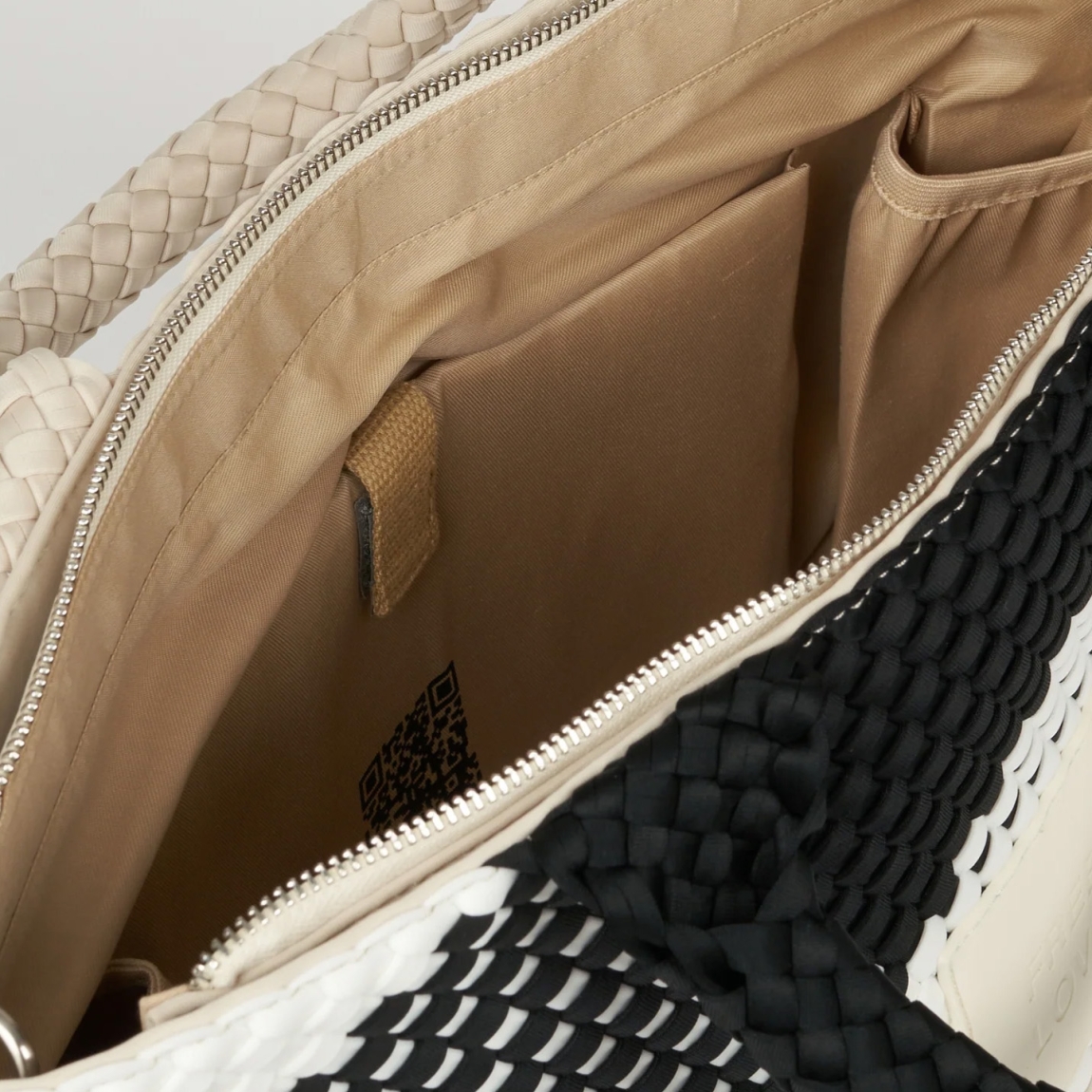 Bolso de la marca VTD, modelo MARAN. Bolso elaborado en neopreno trenzado color blanco y negro, realizado a mano, aporta textura, carácter y una estética atemporal. Un bolso funcional, pero también consciente. Este bolso VTD incorpora una correa ajustable a juego con el color del bolso, que se puede enganchar en el interior, para llevar el bolso al hombro o cruzado, según cómo te muevas. En el interior, varios compartimentos que invitan a ordenar sin esfuerzo, porque cuando todo fluye, tú también. Este bolso VTD, modelo MARAN, está pensado para los días que no tienen un sólo contexto: Para moverte, para cambiar de planes, para llevar lo importante y casi todo lo que quieras contigo!Medidas: alto 27cm y ancho 40cm.