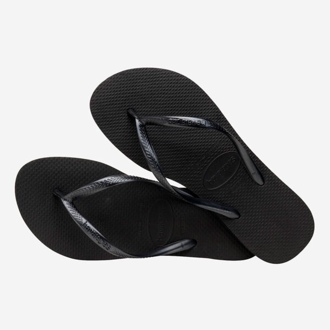 Chanclas de la marca Havaianas, modelo SLIM FC. Chancas elaboradas en plástico color negro. Chanchas con ligereza, la suela de foma suave acompaña el pie sin pesar y el acabado antideslizante te da seguridad tanto en la arena como en el paseo de la tarde. El diseño se centra en estilizar el pie con unas tiras finas que aportan un brillo discreto y muy favorecedor. Cada detalle está pensado para que las chanclas Havaianas SLIM funcionen como una extensión natural de tu estilo: limpias, depuradas y con ese punto elegante que diferencia unas chanclas premium de unas básicas.
