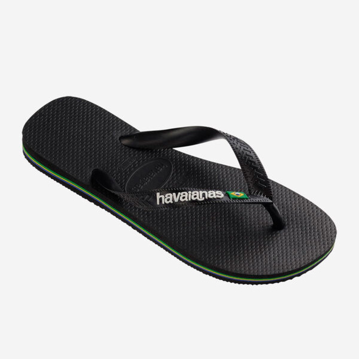 Chanclas de la marca Havaianas, modelo BRASIL. Chancas elaboradas en plástico color negro. Chanchas con ligereza, la suela de foma suave acompaña el pie sin pesar y el acabado antideslizante te da seguridad tanto en la arena como en el paseo de la tarde. El diseño se centra en estilizar el pie con unas tiras finas que aportan un brillo discreto y muy favorecedor, además del logo con la bandera. Cada detalle está pensado para que las chanclas Havaianas BRASIL funcionen como una extensión natural de tu estilo: limpias, depuradas y con ese punto elegante que diferencia unas chanclas premium de unas básicas.