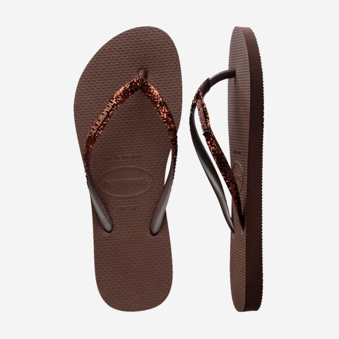 Sandalias de la marca Havaianas, modelo SLIM GLITTER. Chancas elaboradas en plástico color marrón. Chanchas con ligereza, la suela de foma suave acompaña el pie sin pesar y el acabado antideslizante te da seguridad tanto en la arena como en el paseo de la tarde. El diseño se centra en estilizar el pie con unas tiras finas con glitter que aportan un brillo discreto y muy favorecedor. Cada detalle está pensado para que las chanclas Havaianas SLIM GLITTER funcionen como una extensión natural de tu estilo: limpias, depuradas y con ese punto elegante que diferencia unas chanclas premium de unas básicas.