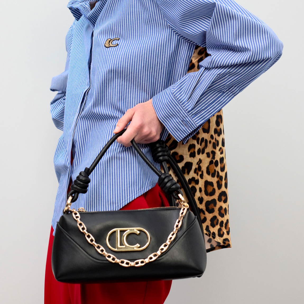 Bandolera elegante de la marca Lola Casademunt, modelo MIKELA. Bolsoelaborado en polipiel color negro, decorada con un asa de nudos y cadena dorada. Incluye pieza inferior ajustable con cierre de cremallera. Bolso Lola Casademunt, modelo MIKELA, con diseño versátil y moderno con el logo destacado.ALTO 12cm ANCHO 26cm PROFUNDIDAD 7cm