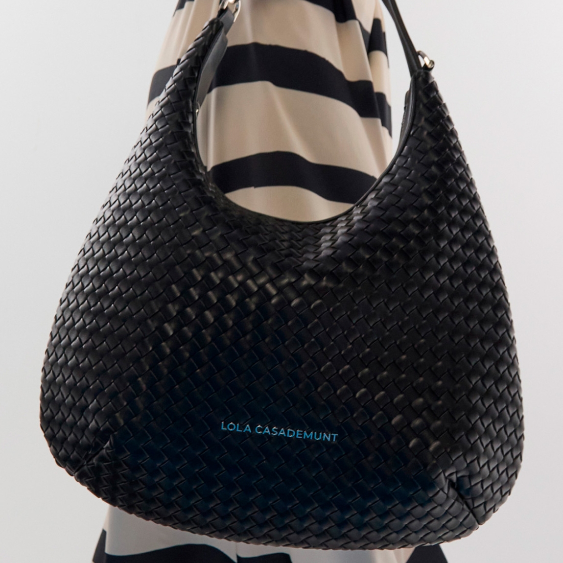 Elegante bolso tipo hobo de la marca Lola Casademunt, modelo CHIARA de diseño trenzado con acabado en negro. Ideal para el día a día, con un espacioso interior y cierre de cremallera. Bolso Lola Casademunt, CHIARA, incluye asa ajustable y detalles metálicos que realzan su estilo moderno. Ideal para llevar tus indispensables a todos lados!ALTO 33cm ANCHO 32cm PROFUNDIDAD 13cm