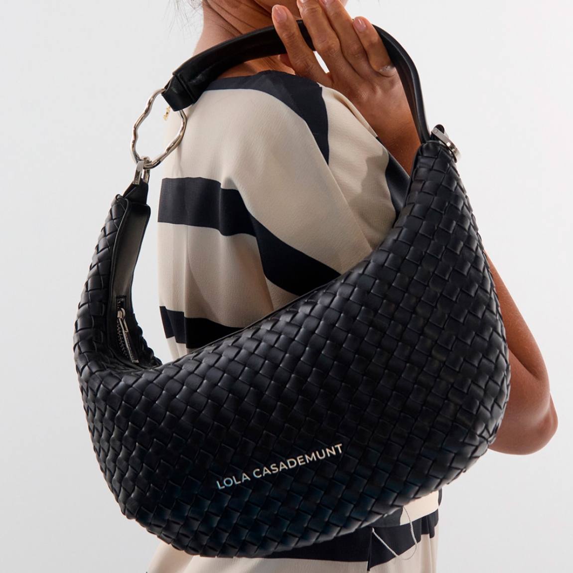 Bolso de diseño media luna de la marca Lola Casademunt, modelo CHIARA_S. Bolso con elegante textura trenzada elaborado en polipiel de color negro . Asa ajustable y desmontable, cierre de cremallera y acabado en sutil tono negro. Bolso Lola Casademunt, CHIARA_S, es un complemento moderno y versátil para cualquier ocasión.ALTO 18cm ANCHO 28cm PROFUNDIDAD 7cm