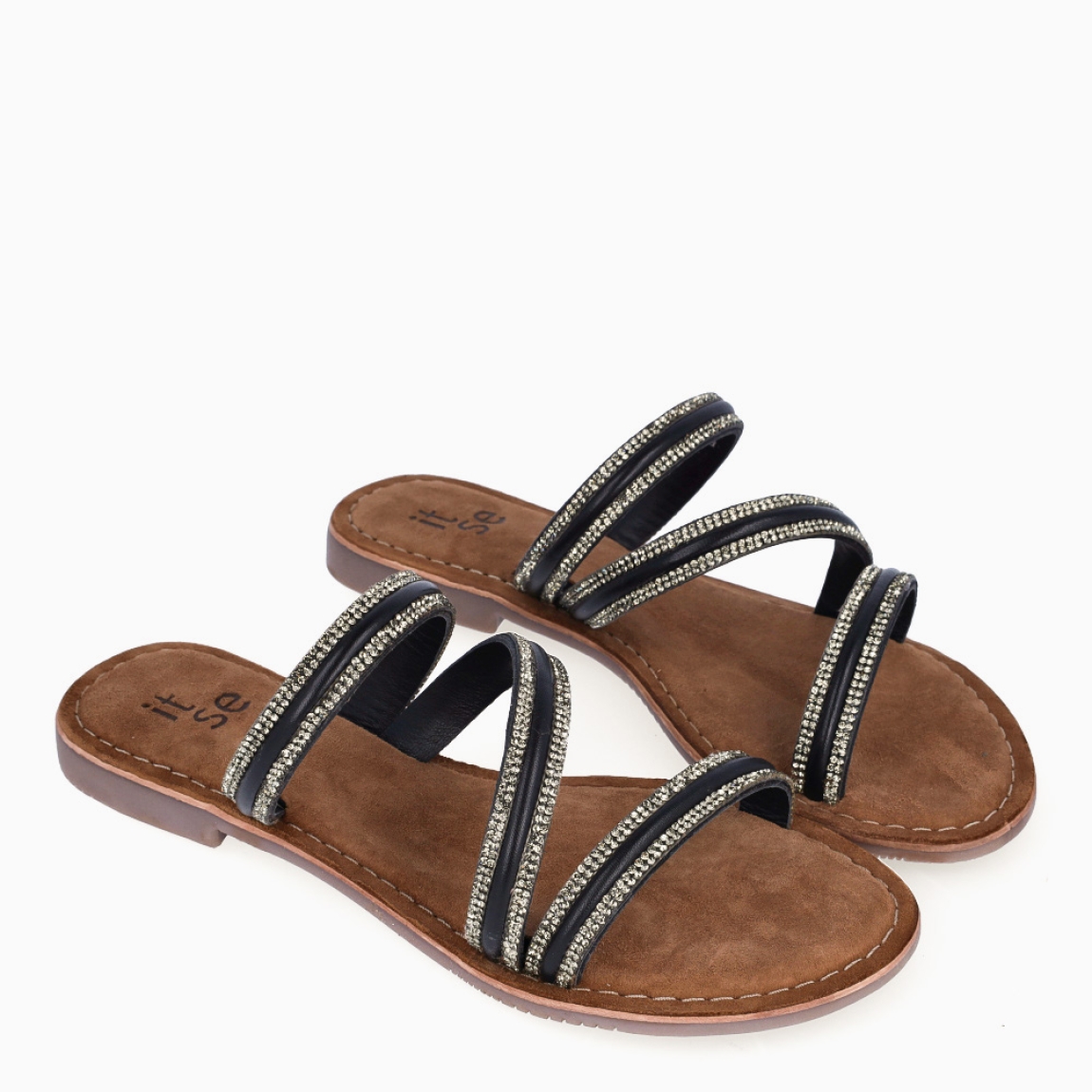 Sandalias de la marca Itse, modelo KENIA. Exterior elaborada en piel color negro con brillantes escarchados color plateado con tiras cruzadas en pala. Interior en ante color marrón. Suela plana de goma. Estas sandalias Itse KENIA son ligeras, cómodas y perfectas para tu día a día!