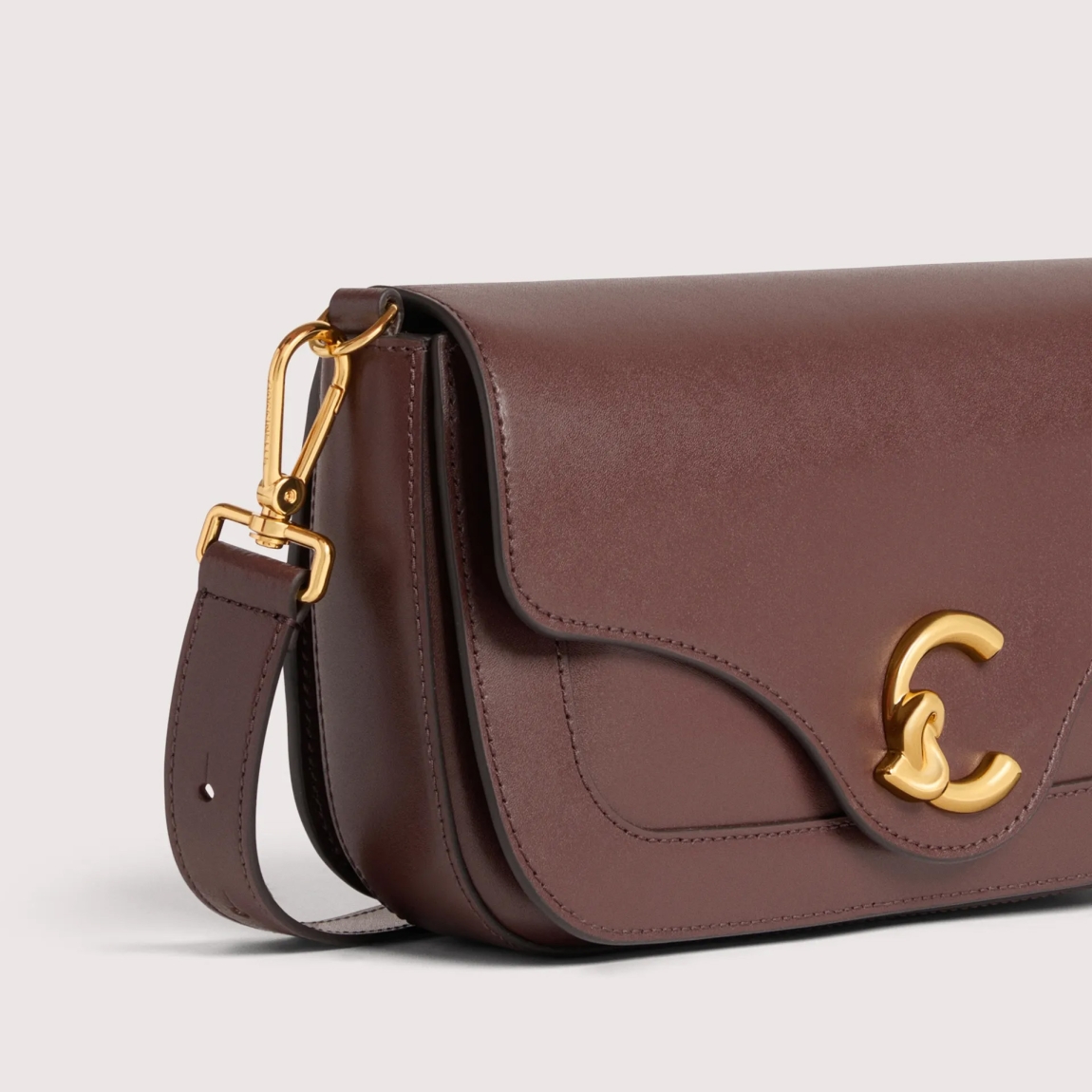 Bolso de la marca Coccinelle, modelo C-ME. Bolso elaborado en piel color burdeos con adorno dorado de logotipo marca. Las líneas geométricas y las elegantes curvas realzan el diseño. Cierre con imán y asa de hombro. Modelo C-ME con un tamaño perfecto para funcionalidad y elegancia. Bolso Coccinelle, modelo que te aportará a tus looks un estilo discreto y refinado. Medidas: alto 15cm y ancho 26cm.
