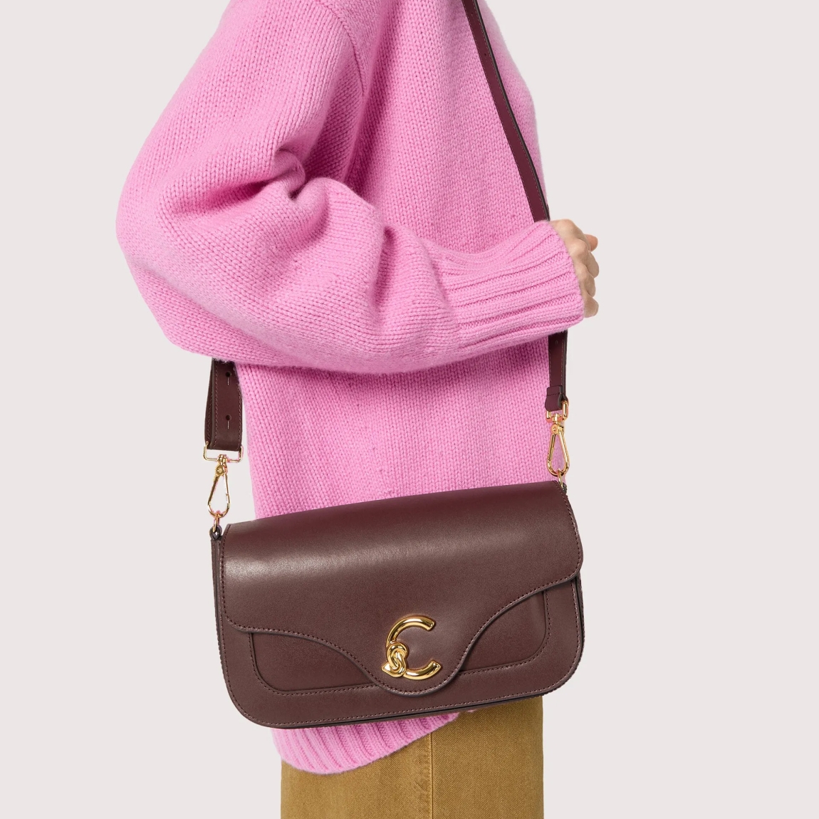 Bolso de la marca Coccinelle, modelo C-ME. Bolso elaborado en piel color burdeos con adorno dorado de logotipo marca. Las líneas geométricas y las elegantes curvas realzan el diseño. Cierre con imán y asa de hombro. Modelo C-ME con un tamaño perfecto para funcionalidad y elegancia. Bolso Coccinelle, modelo que te aportará a tus looks un estilo discreto y refinado. Medidas: alto 15cm y ancho 26cm.