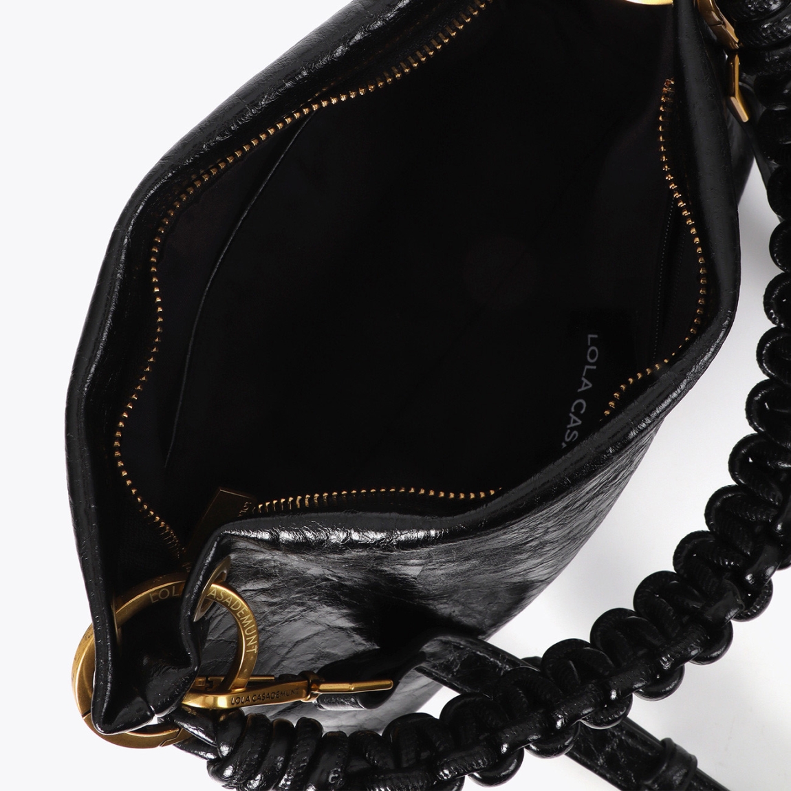 Bandolera pequeña de la marca Lola Casademunt, modelo ALORA. Bolso en cuero texturizado con un elegante asa trenzada color negro. Detalle metálico dorado y cierre superior con cremallera. Ideal para llevar lo esencial con estilo. Diseño versátil y sofisticado, combina con cualquier look diario o de noche. Bolso Lola Casademunt ALORA, ideal para llevarlo a todos lados! Medidas: alto 17cm y ancho 27cm.