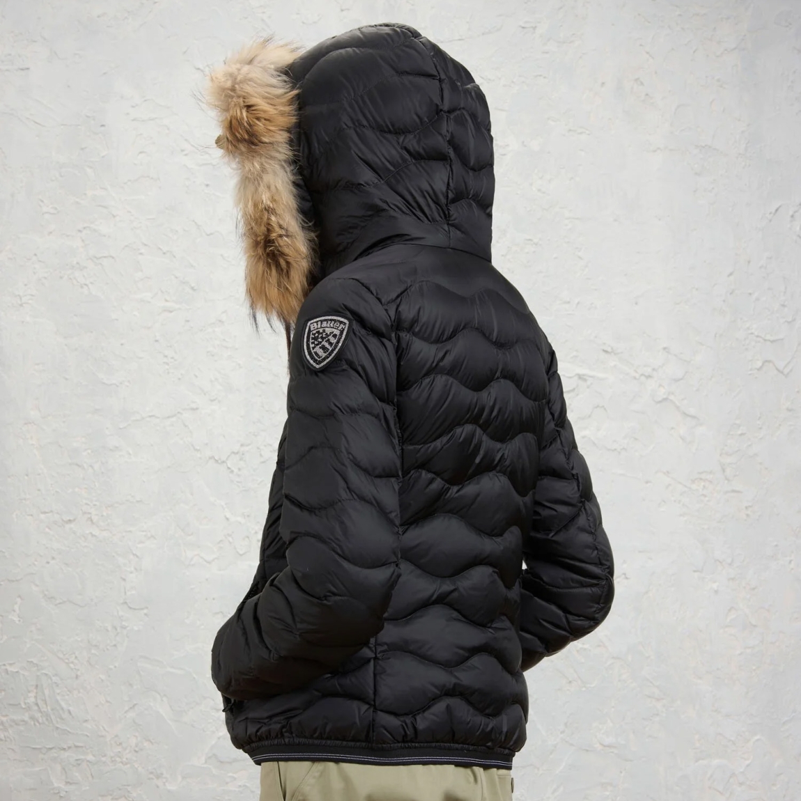 Chaqueta plumífera de la marca Blauer, modelo ALDIE. Chaqueta acolchada con ondas horizontales, embellecido con un borde de capucha en piel auténtica extraíble. Esta prenda icónica de Blauer ofrece un relleno natural (90/10 gr.175) cálido y no voluminoso. Realizado en nylon brillante color negro con forro en contraste, presenta un elegante parche con purpurina. Chaqueta Blauer ALDIE, ideal para los días fríos de esta temporada!
