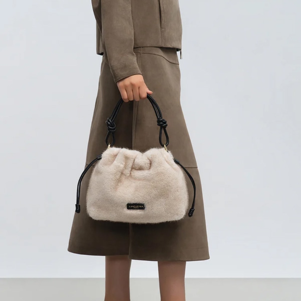 Bolso de la marca Lancaster, modelo MOUMOUTE. Bolso confeccionado en poliéster con detalles en piel de vacuno color crudo. Cuenta con un bolsillo interior con cremallera y un bolsillo sencillo para organizar tus esenciales. Su cierre imantado garantiza practicidad en el día a día. También está equipado con dos cordones ajustables que permiten ceñir los laterales del bolso. Bolso Lancaster MOUMOUTE equipado con un asa corta no ajustable, se lleva en la mano. Su bandolera extraíble y ajustable permite también llevarlo al hombro o cruzado. Ideal para ti!