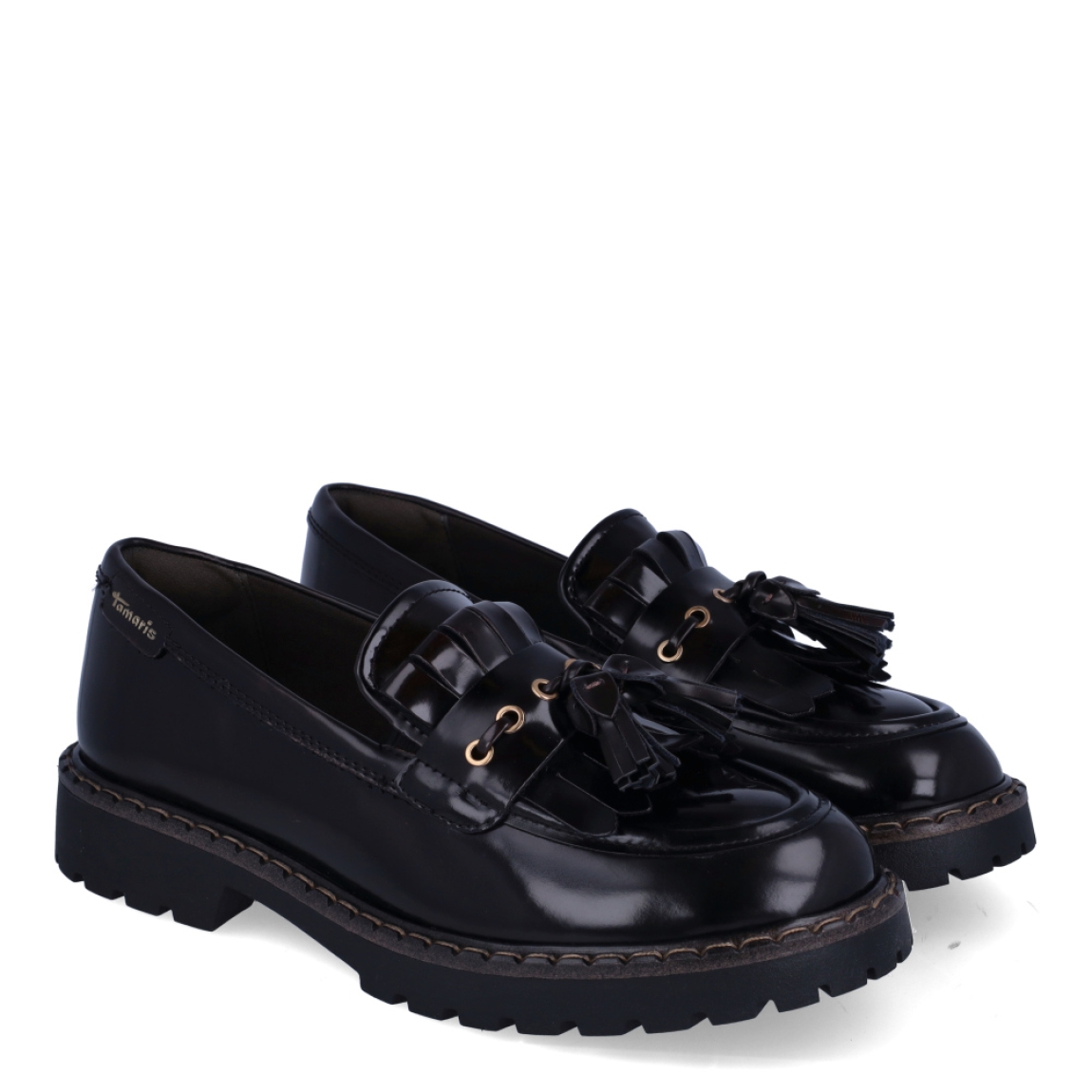 Zapatos estilo mocasín de la marca Tamaris, modelo CAMDEN. Confeccionados en piel de primera calidad con acabado acharolado marrón oscuro, destacan por su diseño clásico con detalle de flecos, borlas y herrajes dorados sobre el empeine. Su horma suave y flexible se adapta fácilmente a todo tipo de pie, ofreciendo un ajuste cómodo desde la primera puesta. Incorporan una plantilla acolchada de alto confort y una suela track de goma dentada con cerco pespunteado, perfecta para aislar del frío y asegurar un agarre impecable. Funcionan genial con calcetines a la vista y minifaldas de tablas, vestidos camiseros o tejanos anchos con jersey de punto grueso. ¡El calzado de tendencia clave para esta temporada!