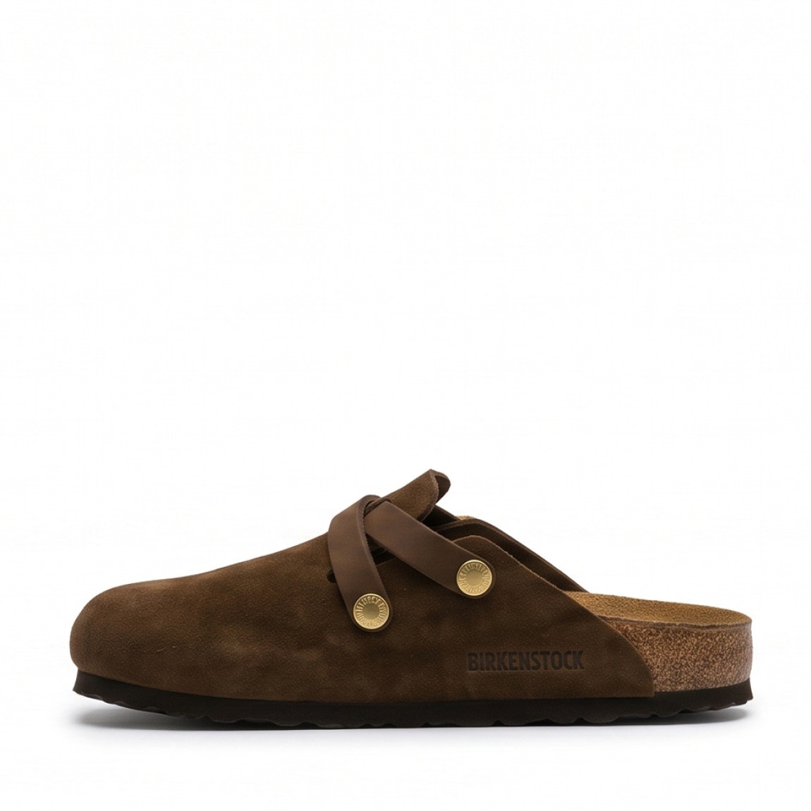 Zuecos de la marca Birkenstock, modelo BLAIR. Zuecos elaborados en piel de ante (serraje) color marrón chocolate, con detalle de tiras cruzadas en el empeine y elegantes hebillas ajustables en acabado dorado. Cuentan con la icónica plantilla anatómica de corcho y látex forrada en piel y suela plana de EVA ligera. Estos zuecos Birkenstock son ideales para complementar tus looks de temporada aunando tendencia y confort. No pueden faltar en tu armario.