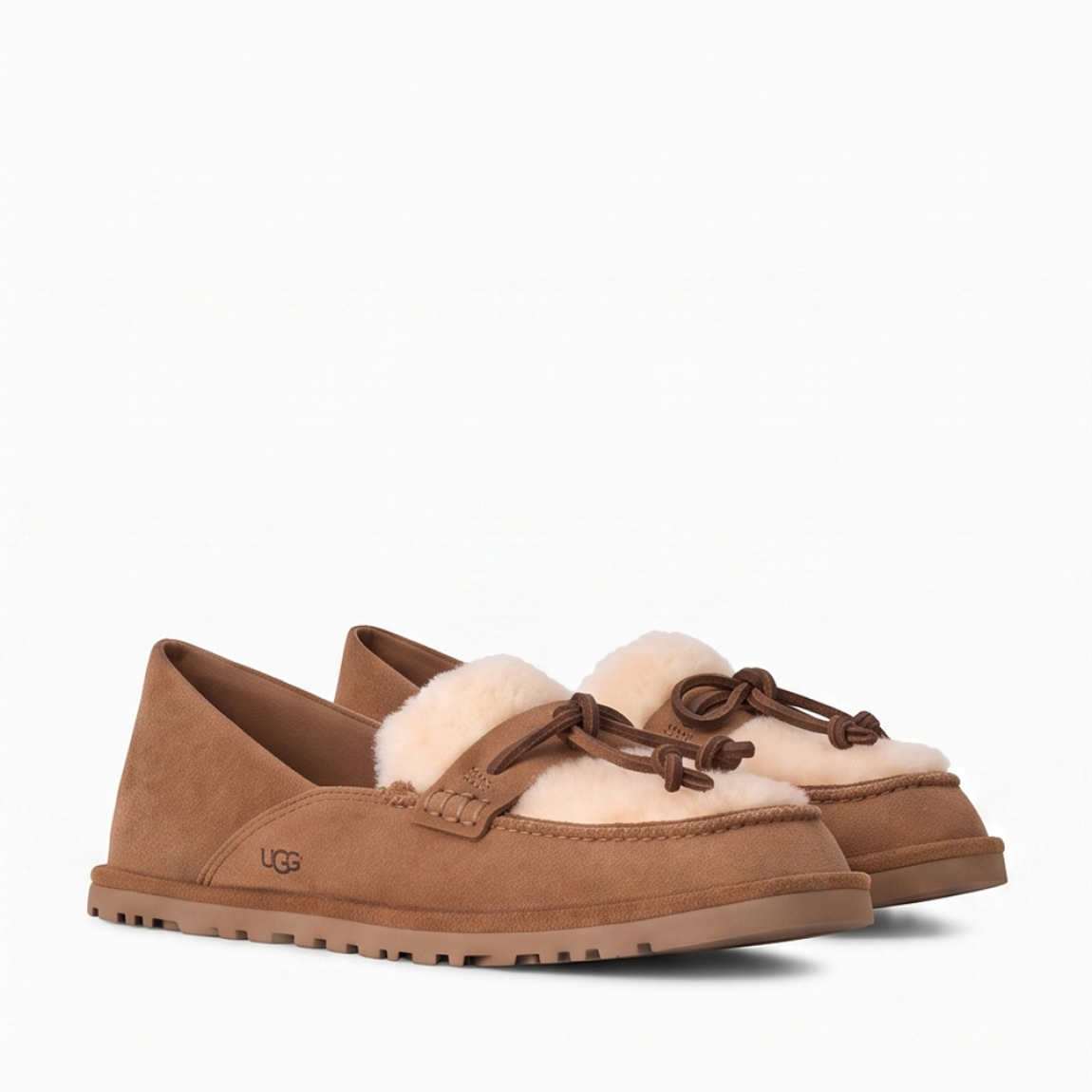 Mocasines de la marca UGG, modelo ZORA. Mocasines elaborados en ante suave color cuero con detalle de lana reciclada UGGplush™ y suave forro de piel de oveja a la vista. Logotipo de UGG grabado en el lateral. Diseño sin cordones con tira y nudo decorativo de piel en el empeine. Suela de goma ligera y dentada para mayor tracción. Perfectos para acompañarte en tu día a día, ideales para combinar con vaqueros rectos o conjuntos casuales tanto en tus planes de fin de semana como en tus paseos por la ciudad. ¡Estos mocasines UGG ZORA son un complemento ideal en comodidad y estilo!