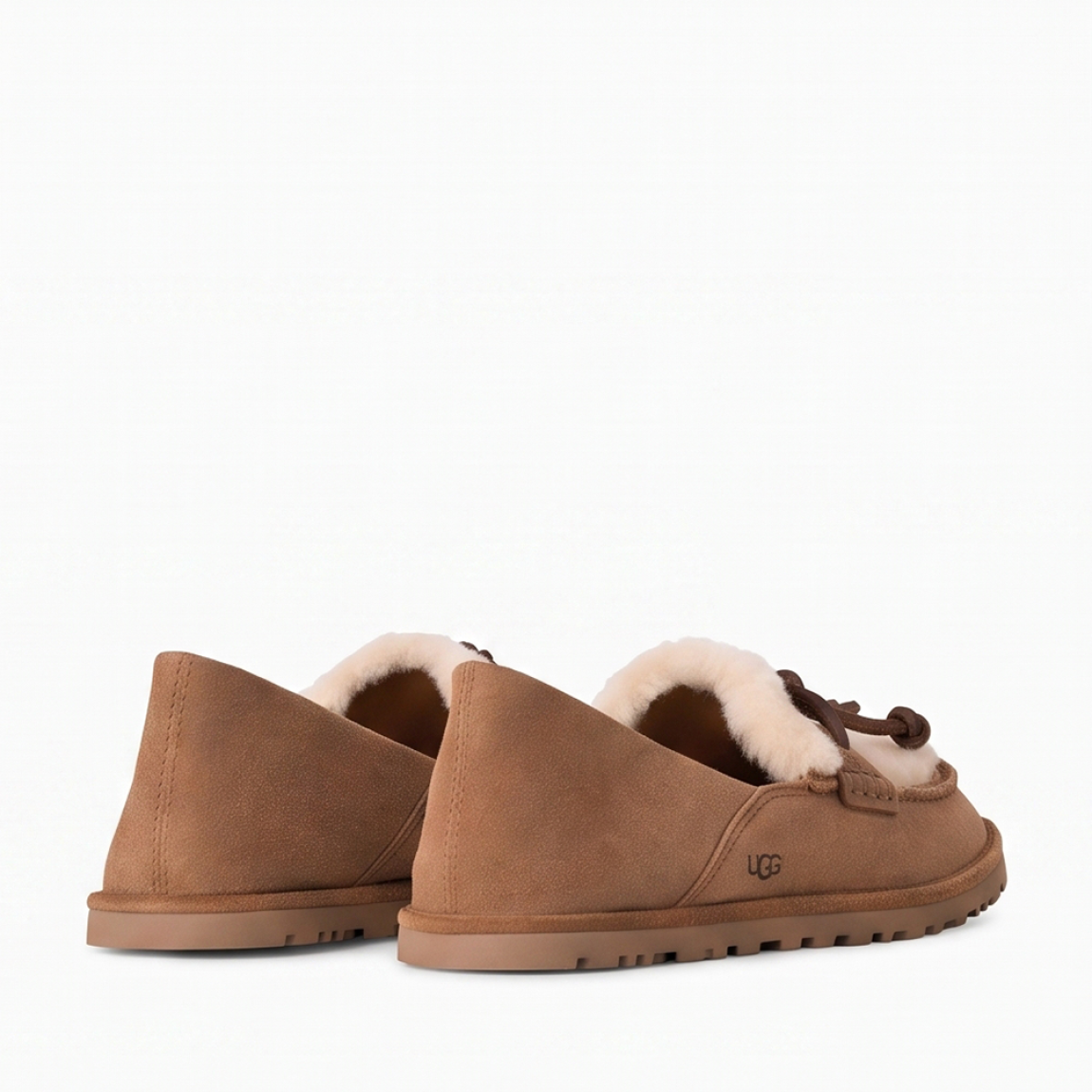 Mocasines de la marca UGG, modelo ZORA. Mocasines elaborados en ante suave color cuero con detalle de lana reciclada UGGplush™ y suave forro de piel de oveja a la vista. Logotipo de UGG grabado en el lateral. Diseño sin cordones con tira y nudo decorativo de piel en el empeine. Suela de goma ligera y dentada para mayor tracción. Perfectos para acompañarte en tu día a día, ideales para combinar con vaqueros rectos o conjuntos casuales tanto en tus planes de fin de semana como en tus paseos por la ciudad. ¡Estos mocasines UGG ZORA son un complemento ideal en comodidad y estilo!