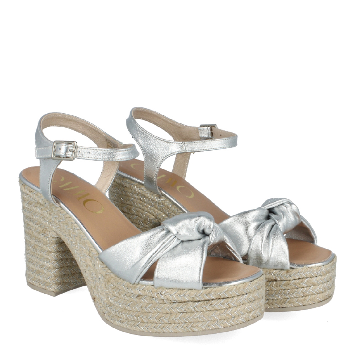 Sandalias de la marca Gaimo, modelo COQUE. Exterior de las sandalias en piel color plata con detalle de nudo en la pala. Interior de las sandalias en piel color nude. Cierre de las sandalias Gaimo con hebilla en el tobillo. Sandalias con tacón de 9cm de altura. Estas sandalias Gaimo COQUE son una tendencia de temporada, con las que te sentirás cómoda y con estilo en tu día a día.