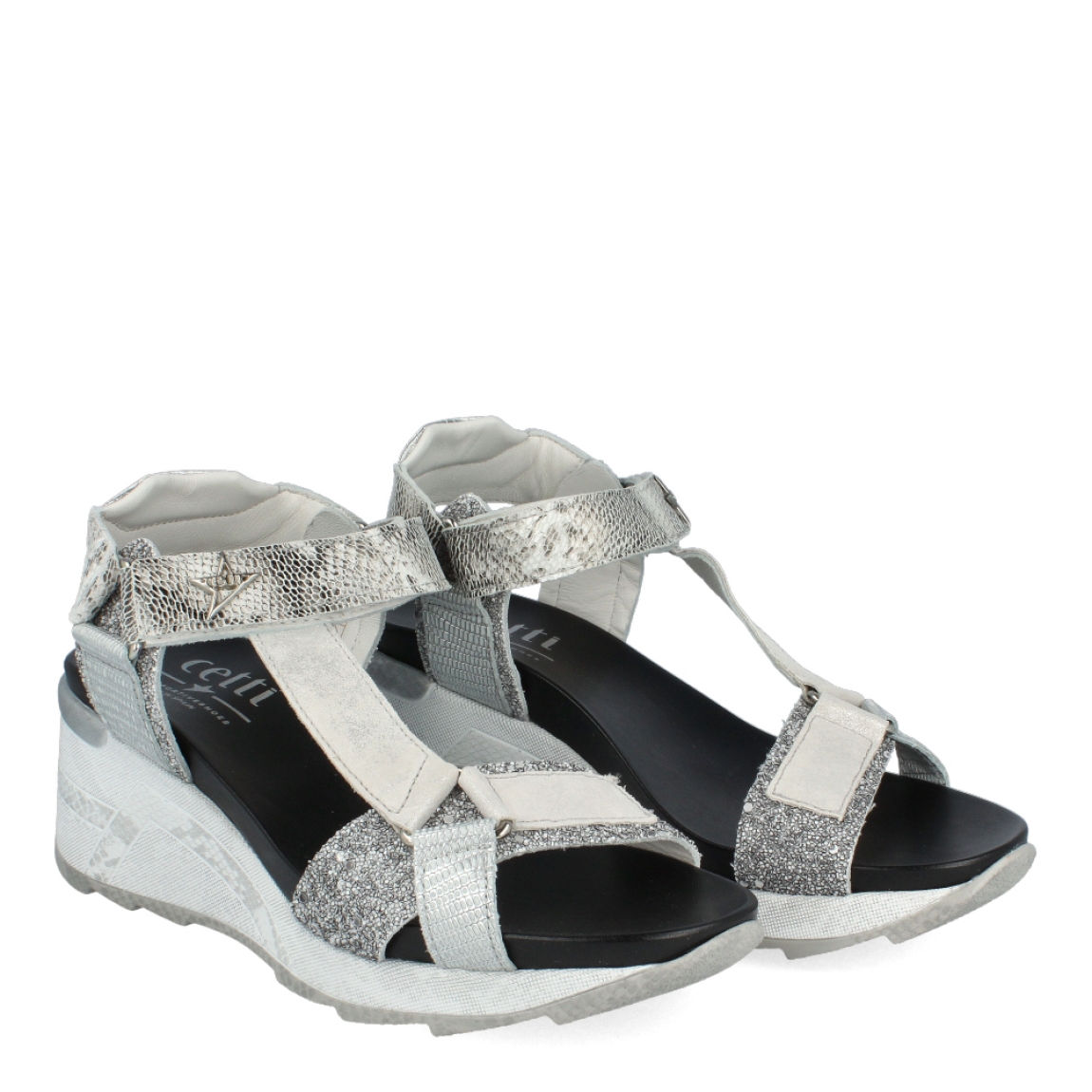 Sandalias de la marca Cetti, modelo SAGA. Exterior de las sandalias en piel color plata. Interior de las sandalias en piel color negro. Cierre de las sandalias con velcro en el tobillo. Sandalias Cetti con cuña de 5cm de altura. Estas sandalias Cetti SAGA, tienen el diseño perfecto para lucirlas con estilo y comodidad.