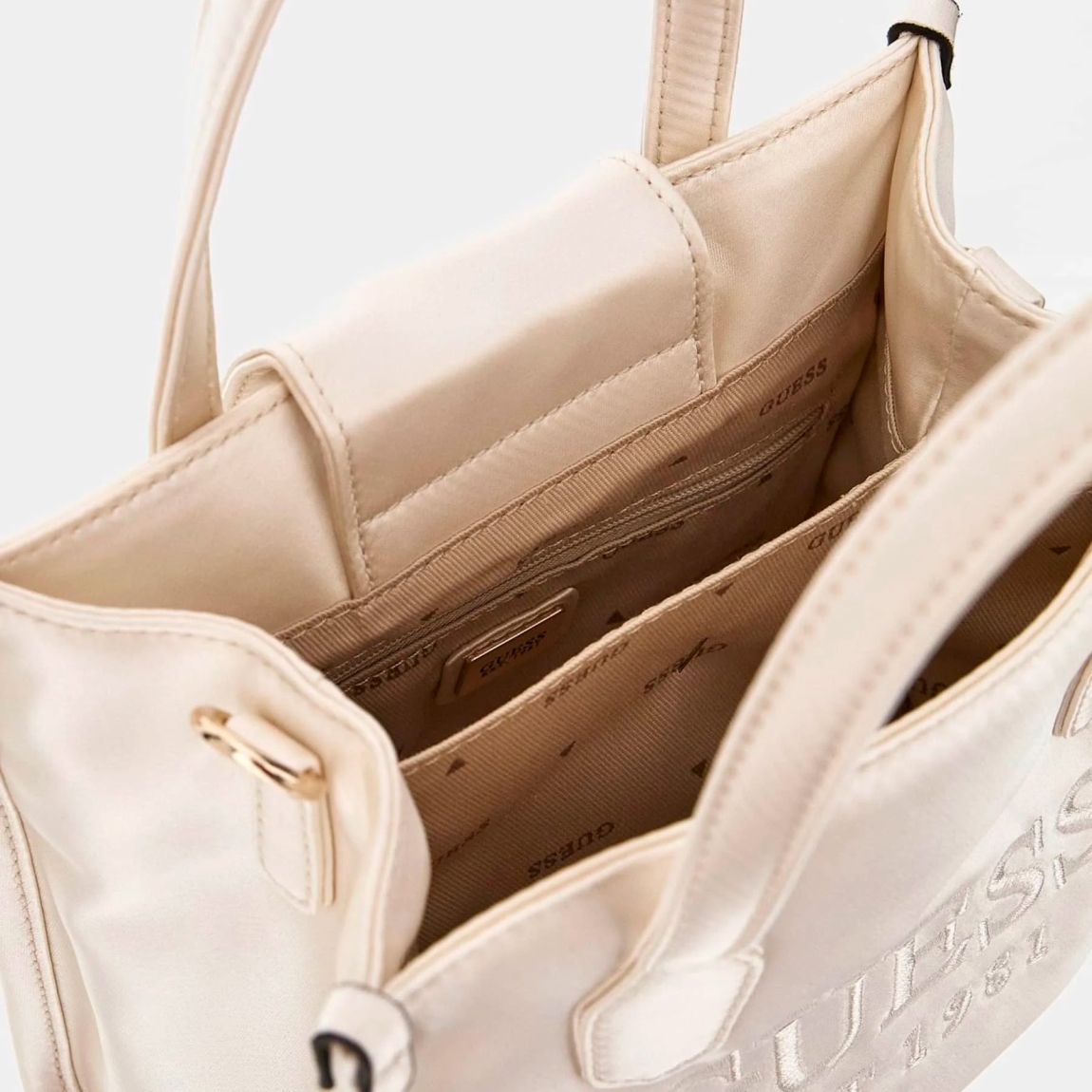 Bolso de la marca Guess, modelo SILVANA. Exterior del bolso en tela color blanco con estampado del logotipo en la parte frontal. Interior del bolso en textil con estampado, bolsillo y doble compartimento. Cierre del bolso Guess con botón y doble asa, una fija, otra justable y extraíble. Medidas: alto 17cm y ancho 20cm. Este bolso Guess SILVANA tiene el diseño ideal para llevarlo a donde quieras con la comodidad y estilo único durante esta temporada.