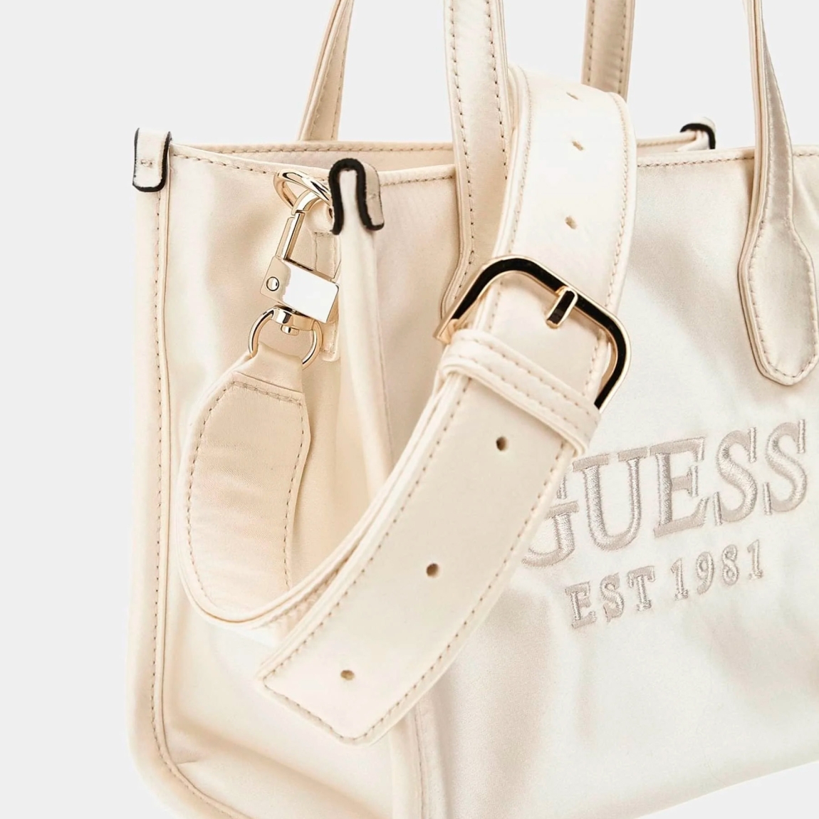 Bolso de la marca Guess, modelo SILVANA. Exterior del bolso en tela color blanco con estampado del logotipo en la parte frontal. Interior del bolso en textil con estampado, bolsillo y doble compartimento. Cierre del bolso Guess con botón y doble asa, una fija, otra justable y extraíble. Medidas: alto 17cm y ancho 20cm. Este bolso Guess SILVANA tiene el diseño ideal para llevarlo a donde quieras con la comodidad y estilo único durante esta temporada.