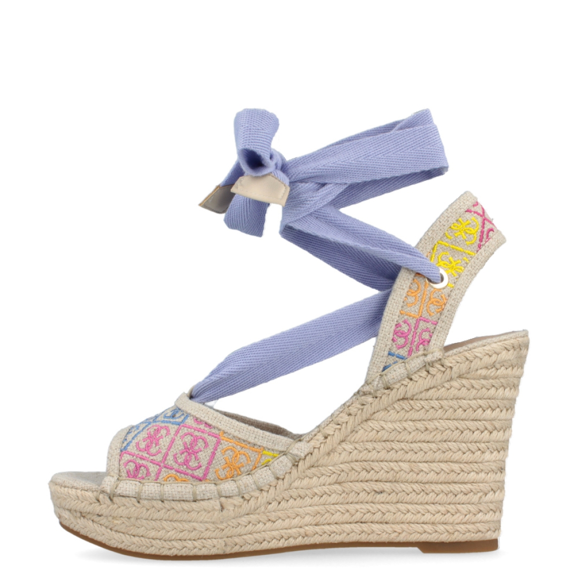 Sandalia multicolor de la marca Guess, modelo Halona. Exterior de la sandalia de tela de color beig, con logo 4G bordado multicolor. Interior de la sandalia de piel de color beig. Sandalia con lazo de color lila en el tobillo. Cierre de la sandalia con velcro y correa en el tobillo. Sandalia con suela de rafia de 10 cm de cuña, con 4 cm de plataforma. La sandalia Halona de Guess es ideal para dar un toque de color a tus looks.
