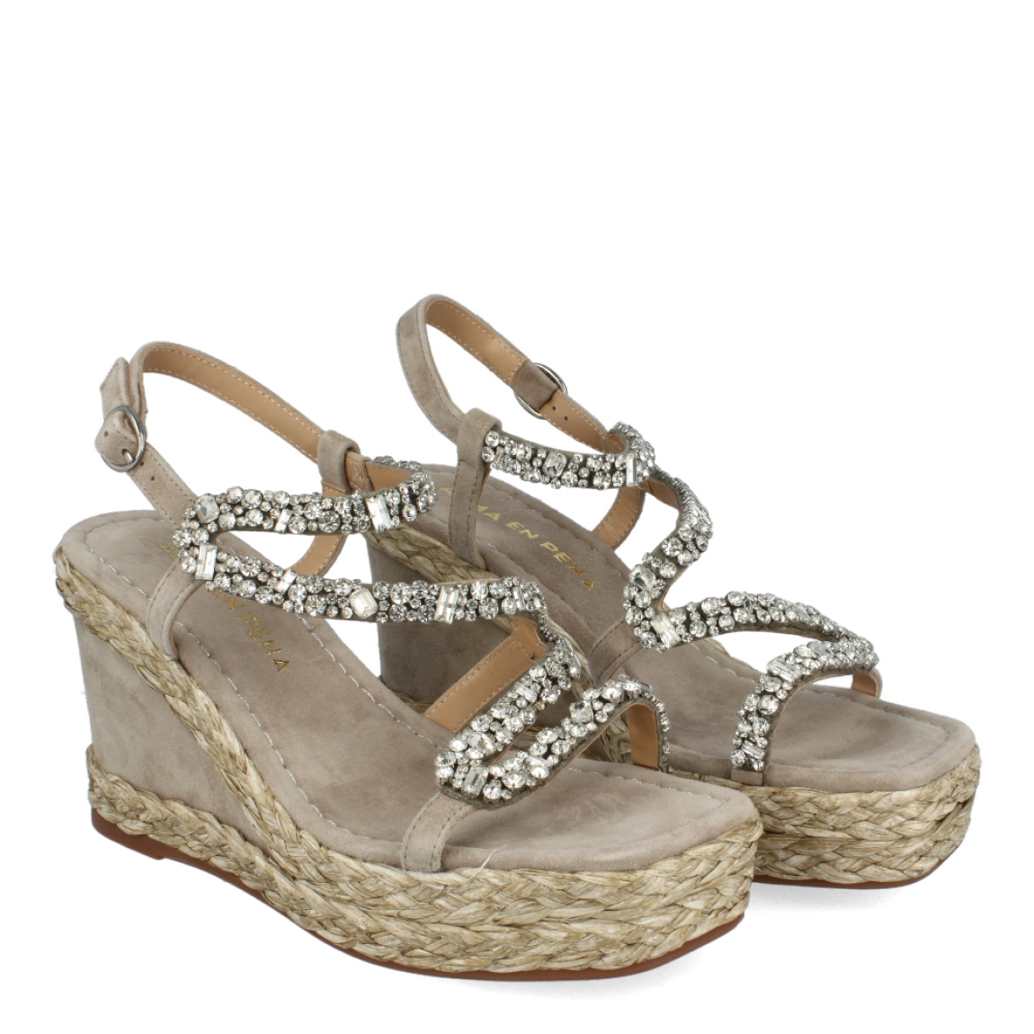 Sandalias de la marca Alma en Pena, modelo BECCA. Exterior de las sandalias en ante color taupe con tiras brillantes. Interior de las sandalias en ante color taupe. Cierre de sandalias Alma en pena con hebilla y cuña de 9cm de altura. Estas sandalias Alma en Pena BECCA tienen el diseño perfecto para quienes le gusta la elegancia y comodidad. Un complemento perfecto para resaltar tus looks de temporada con la máxima comodidad posible.