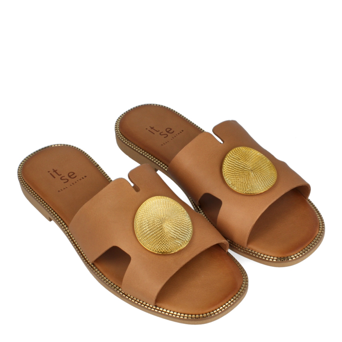 Chanclas de la marca Itse, modelo TALIA. Chanclas elaboradas en piel color cuero con detalle de círculo metal dorado en la pala. Chanclas con suela plana. Estas chanclas Itse TALIA son un complemento ideal para gozar de la máxima comodidad en tu día a día. No te puede faltar en el armario.