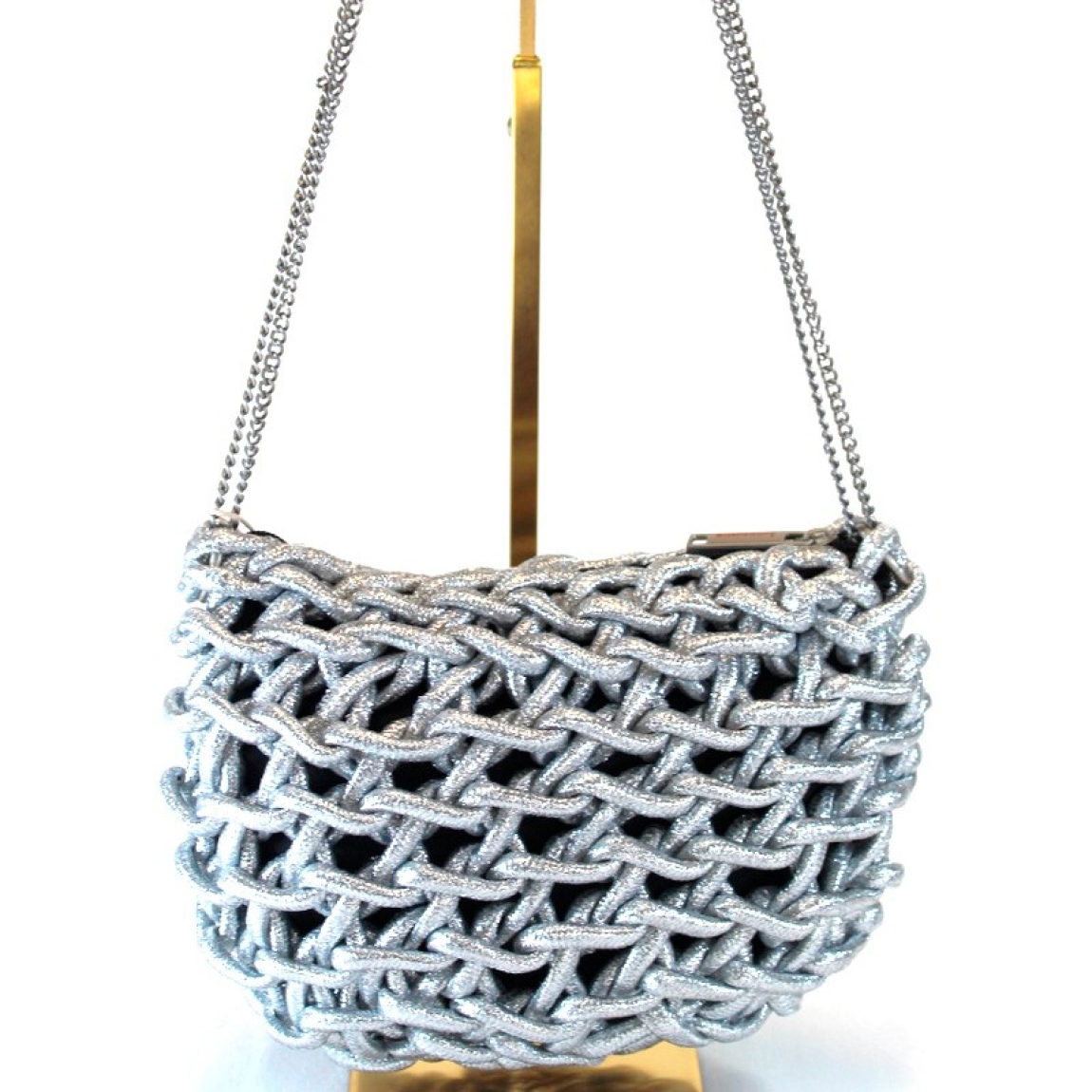Bolso de la marca Simosastre, modelo JANETH. Bolso cruzado de cuerda elaborado en tela color plata con logo de acero en parte frontal. Cierre del bolso con cremallera y bandolera en metal en oro. Medidas del bolso:a lto 17cm y ancho 23cm. Este bolso Simosastre JANETH es un complemento ieal para darle estilo y personalidad a tus looks de temporada.