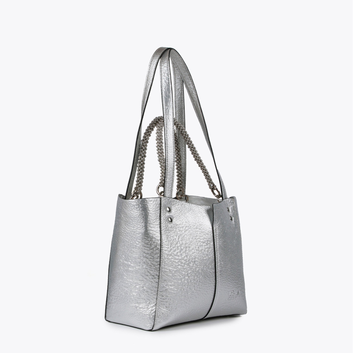 Bolso mediano de la marca Lola Casademunt, modelo LEA. Bolso en efecto piel metalizado color plata con asa metálica decorativa. Contiene pouch interior. Cierre imantado.ALTO: 23 cm - LARGO: 27 cm - ANCHO: 11 cm / BANDOLERA: 58 cm
