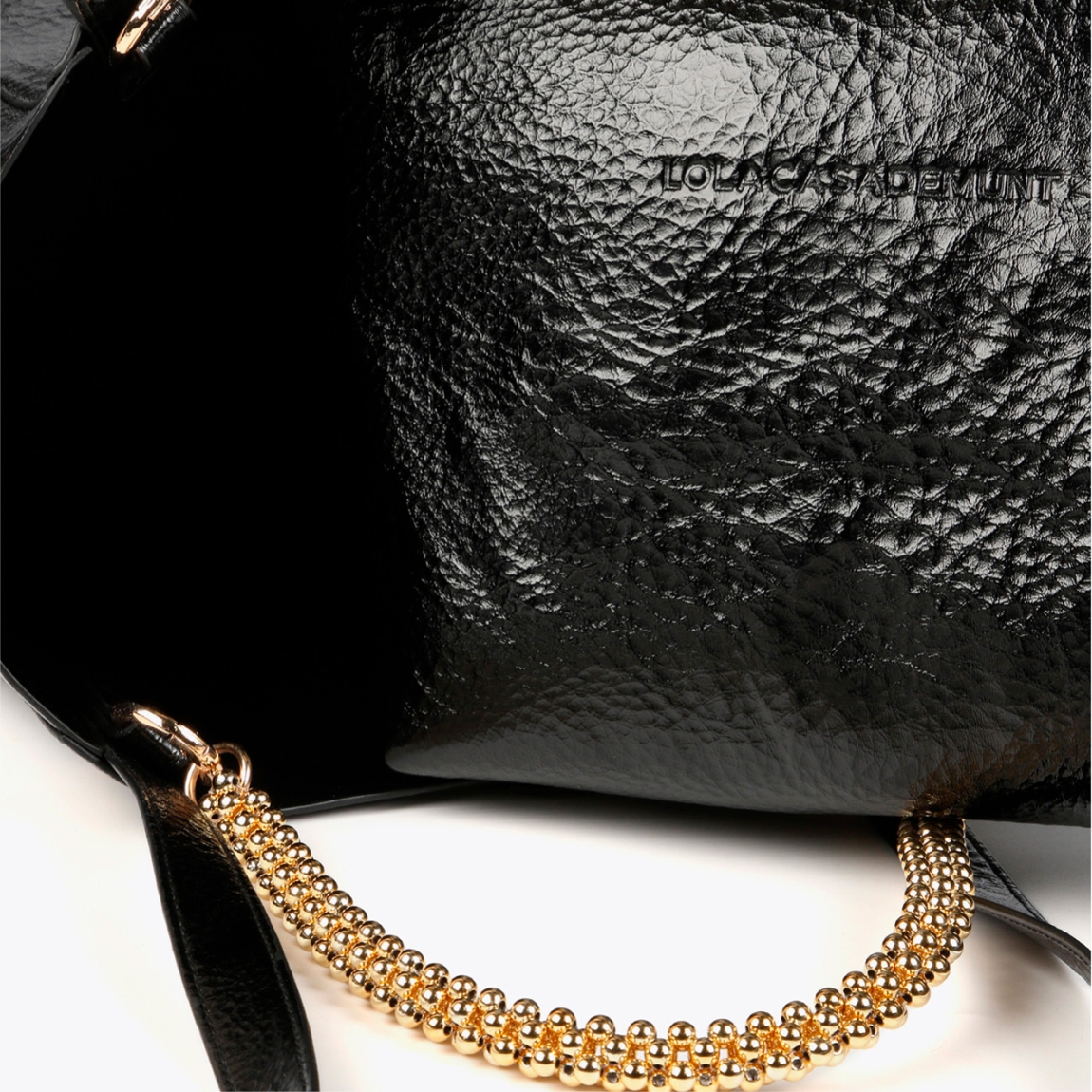 Bolso mediano de la marca Lola Casademunt, modelo LEA. Bolso en efecto piel metalizado color negro con asa metálica decorativa. Contiene pouch interior. Cierre imantado.ALTO: 23 cm - LARGO: 27 cm - ANCHO: 11 cm / BANDOLERA: 58 cm