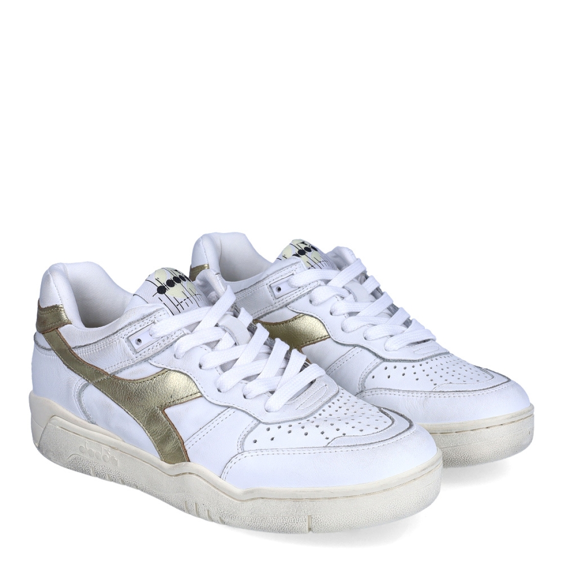 Deportivas de la marca Diadora, modelo B560. Exterior en piel troquelada color blanco con detalles en dorado. Interior en textil color blanco, con plantilla acolchada y extraíble para máxima comodidad. Cierre con cordones de color blanco. Suela de goma con cuña de 3cm de altura. Estas deportivas B560 son unas clásicas ideales para llevar en tu día a día.