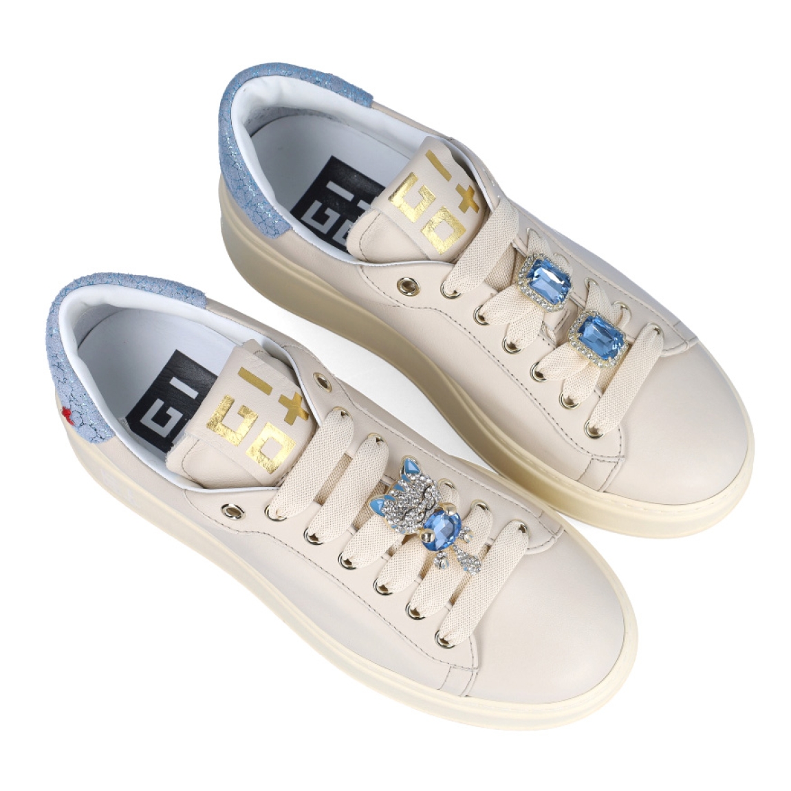 Deportivas de la marca GIO+, modelo PIA. Exterior en piel color beig con detalle de brillantes color celeste en el talón. Interior en piel blanca con plantilla acolchada y extraíble para máxima comodidad. Cierre de las deportivas con cordones, y adornos en forma de gato con piedreria azul sobre la pala. Plataforma de 4cm de altura. Estas deportivas GIO+ PIA son las clásicas con el toque de estilo moderno que necesitas en tus looks de temporada!