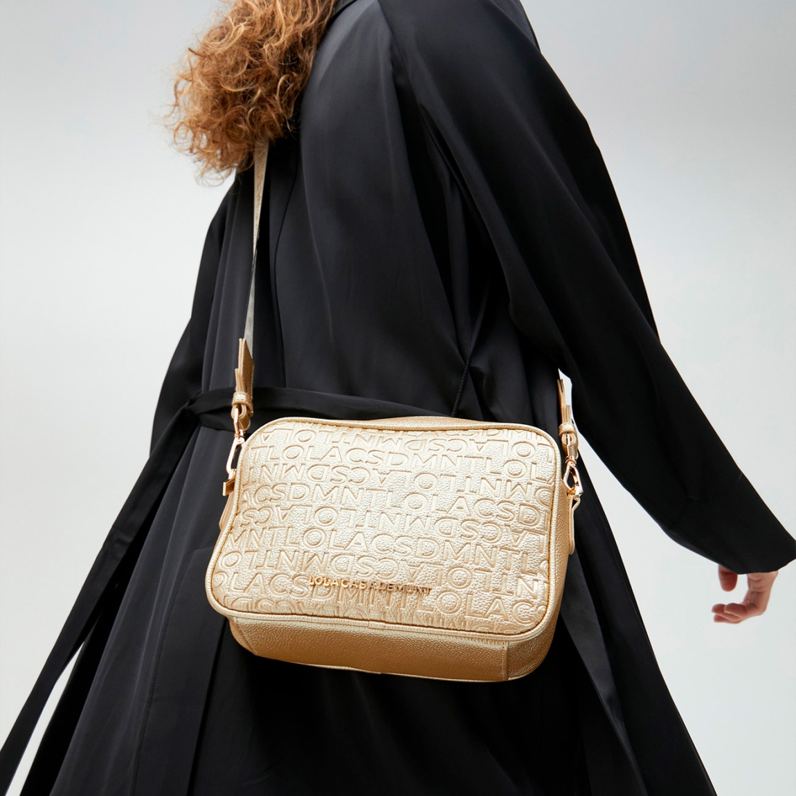 Bolso de la marca Lola Casademunt, modelo NORA. Bolso bandolera en efecto piel metalizado color oro. Detalle de grabado monograma. Contiene asa bandolera ajustable. Cierre con cremallera.ALTO: 25 cm - LARGO: 17 cm - ANCHO: 8 cm / BANDOLERA: 126 cm