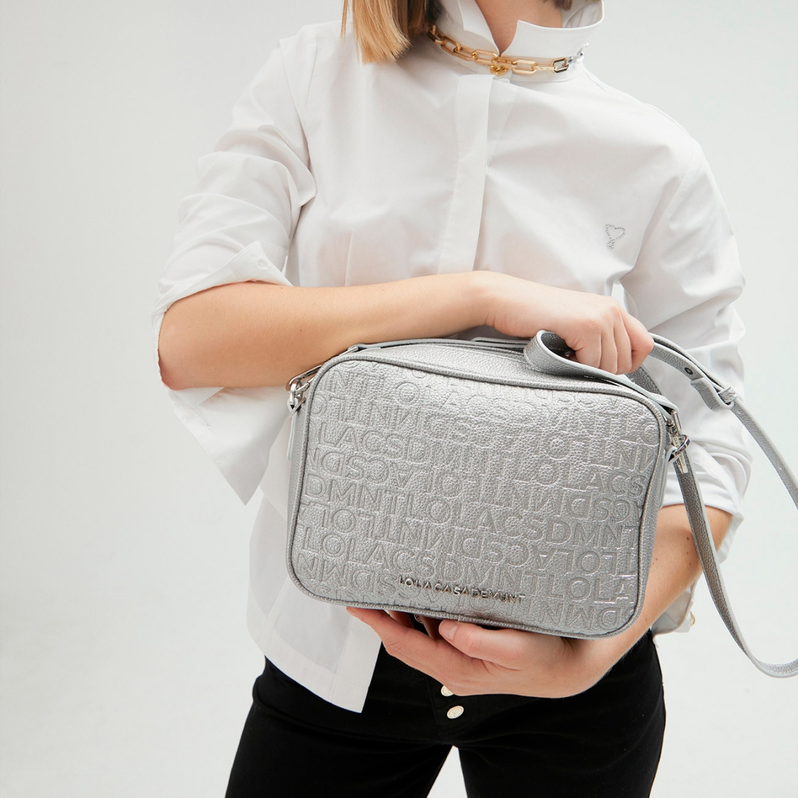 Bolso de la marca Lola Casademunt, modelo NORA. Bolso bandolera en efecto piel metalizado. Detalle de grabado monograma. Contiene asa bandolera ajustable. Cierre con cremallera.ALTO: 25 cm - LARGO: 17 cm - ANCHO: 8 cm / BANDOLERA: 126 cm