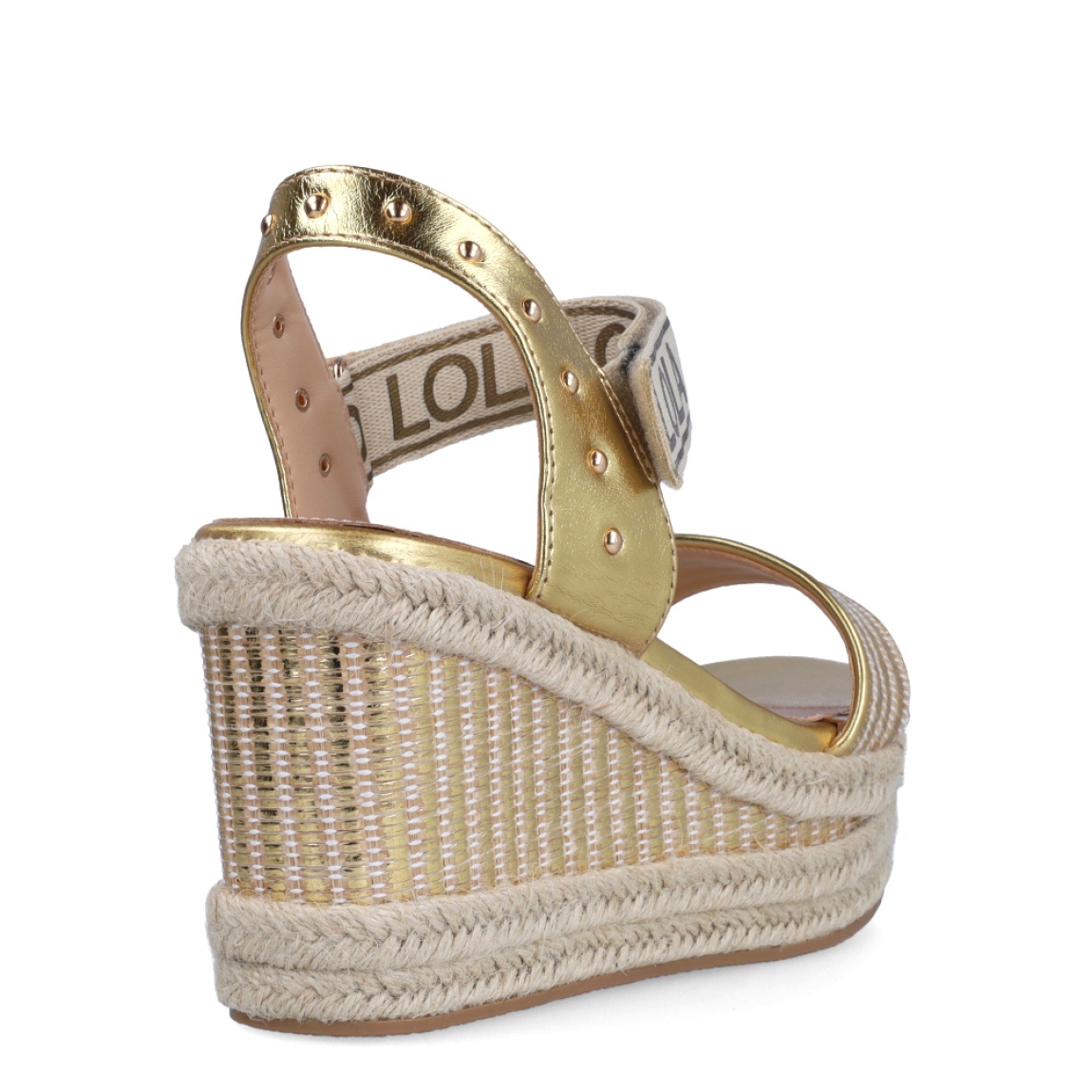 Sandalias de la marca Lola Casademunt, modelo INTI. Exterior en piel color platino con detalle de tachuelas. Interior en piel color beig. Cierre con velcro con estampado de marca. Sandalias con cuña de 9cm de altura. Estas sandalias Lola Casademunt INTI son un complemento que le dará estilo a tus looks!