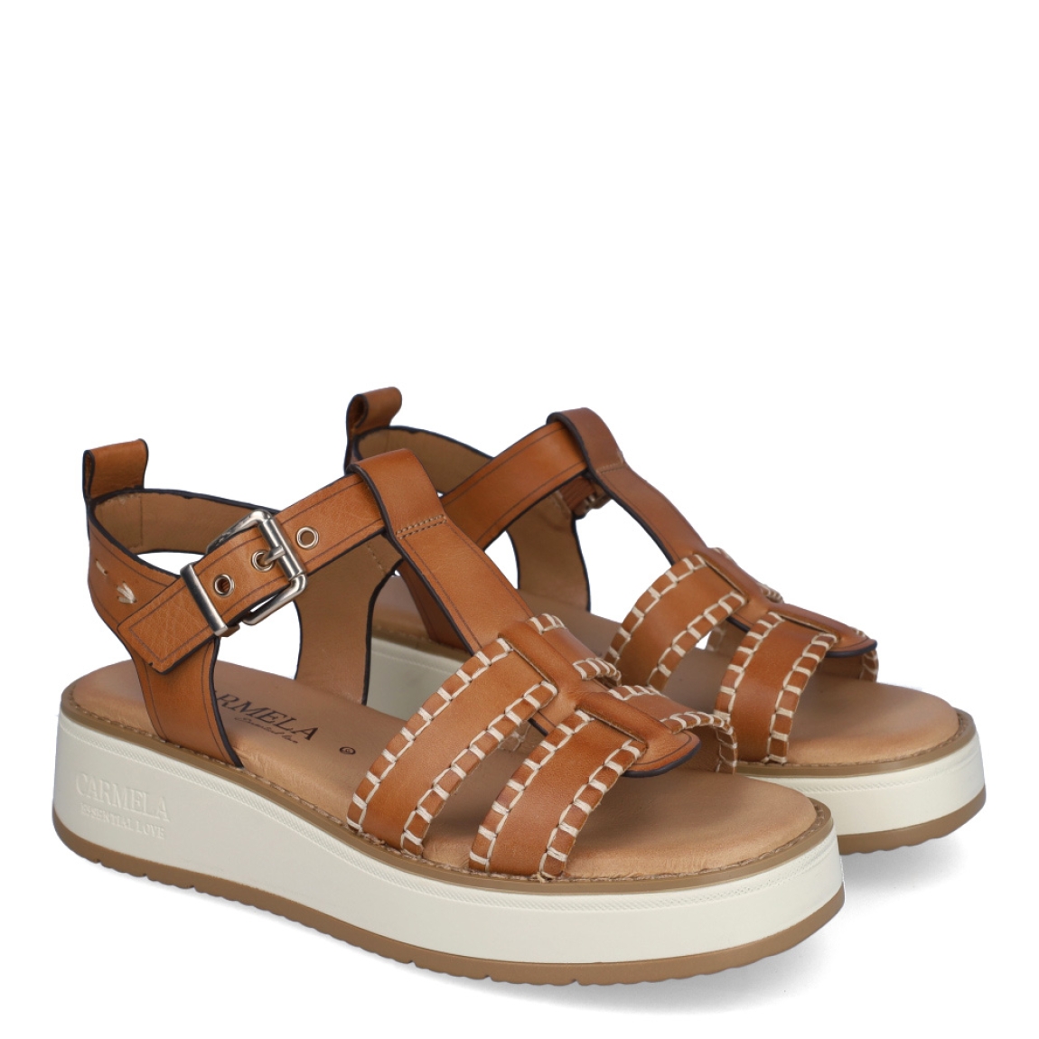 Sandalias de la marca Carmela, modelo LION. Exterior en piel color camel con tiras en pala. Interior en piel color nude con plantilla acolchada. Cierre con hebilla en la pala. Sandalias Carmela con cuña de 4cm de altura. Estas sandalias Carmela LION son ideales para gozar de comodidad en tu día a día.