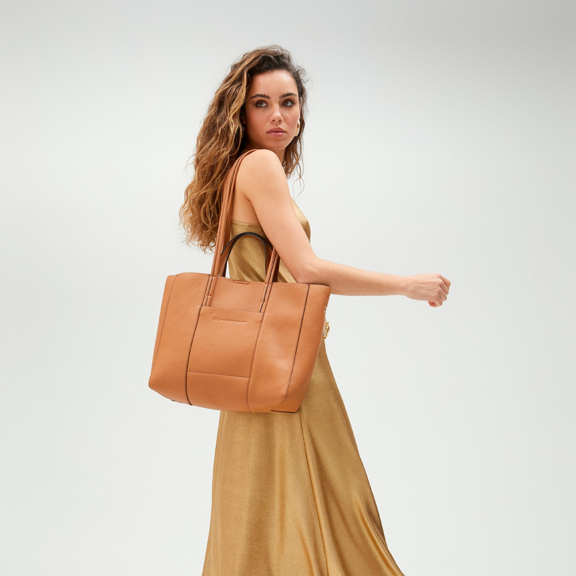 Bolso shopper de la marca Lola Casademunt, modelo KERENT. Exterior en piel color camel con interior en material glitter dorado. Contiene distintos compartimentos interiores y bolsillos con cremallera. Contiene asa bandolera ajustable. Cierre imantado. ALTO: 28 cm - LARGO: 45 cm - ANCHO: 12 cm / BANDOLERA: 28 cm. Este bolso Lola Casademunt KERENT es el complemento ideal para llevar todos tus esenciales en tu día a día!