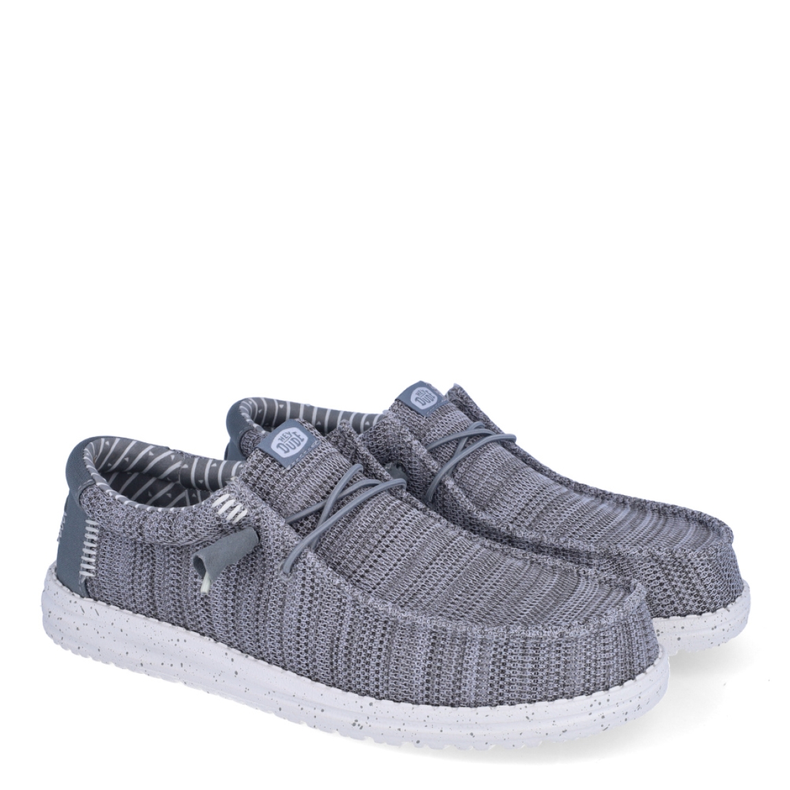 Náuticos de la marca Hey Dude, modelo WALLY STRECH. Exterior de los náuticos en tela color gris. Interior de los náuticos en tela con estampado gris y plantilla acolchada y extraíble. Cierre de los náuticos Hey Dude con cordones elásticos y suela plana de goma. Estos náuticos Hey Dude WALLY STRECH, son el complemento perfecto para esta temporada, los podrás lucir con la máxima comodidad posible.