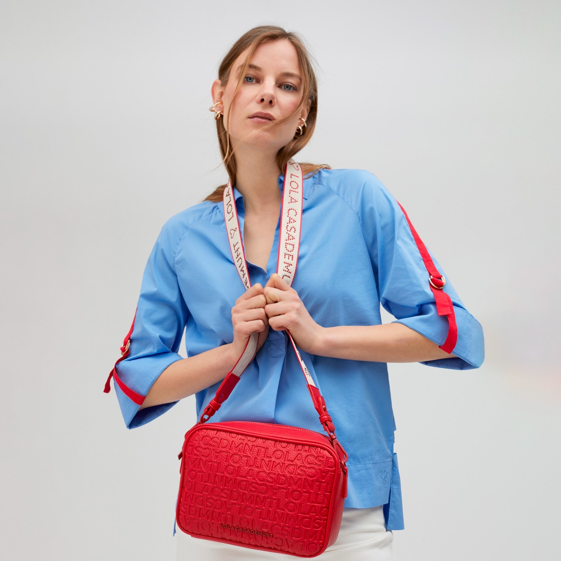 Bolso de la marca Lola Casademunt, modelo GEMMA. Bolso Bandolera con grabado monograma en efecto piel color rojo. Contiene asa bandolera con detalle de logo en strass. Cierre con cremallera.ALTO: 25 cm - LARGO: 17 cm - ANCHO: 8 cm / BANDOLERA: 126 cm