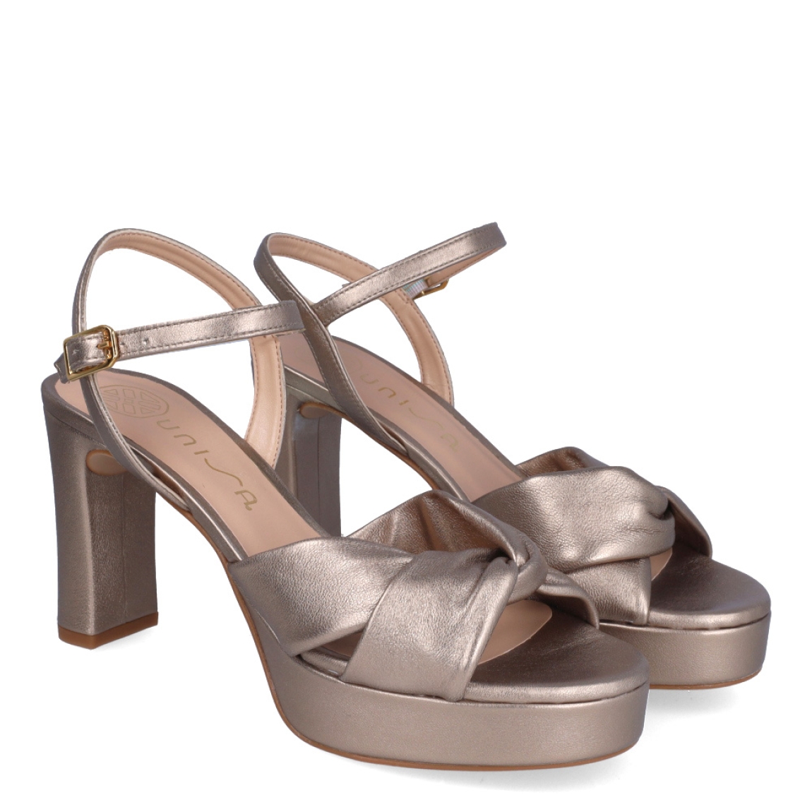 Sandalias de la marca Unisa, modelo ONOA. Exterior en piel color platino con pala cruzada. Interior en piel color nude. Cierre de sandalias Unisa con hebilla en tobillo y un tacón de 8cm de altura. Estas sandalias Unisa ONOA son un complemento clásico e ideal para lucir tus looks de esta temporada!