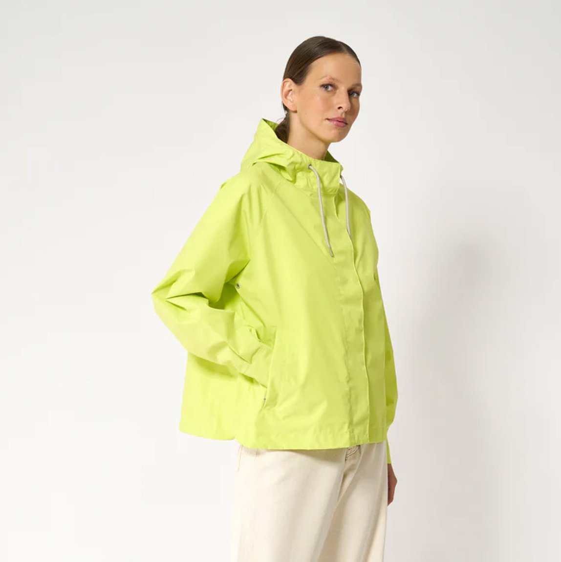 Chaqueta impermeable corta de la marca Tanta, modelo Dhuda. Tiene corte holgado y está confeccionada con un tejido de mezcla de algodón impermeable color fluor. Este material atemporal es transpirable y resistente al viento. Los detalles de la prenda incluyen costuras selladas, mangas raglán, una cremallera de doble cursor y cierres a presión ocultos. Su elegante silueta en línea A cuenta con aberturas laterales redondeadas para un look más femenino.